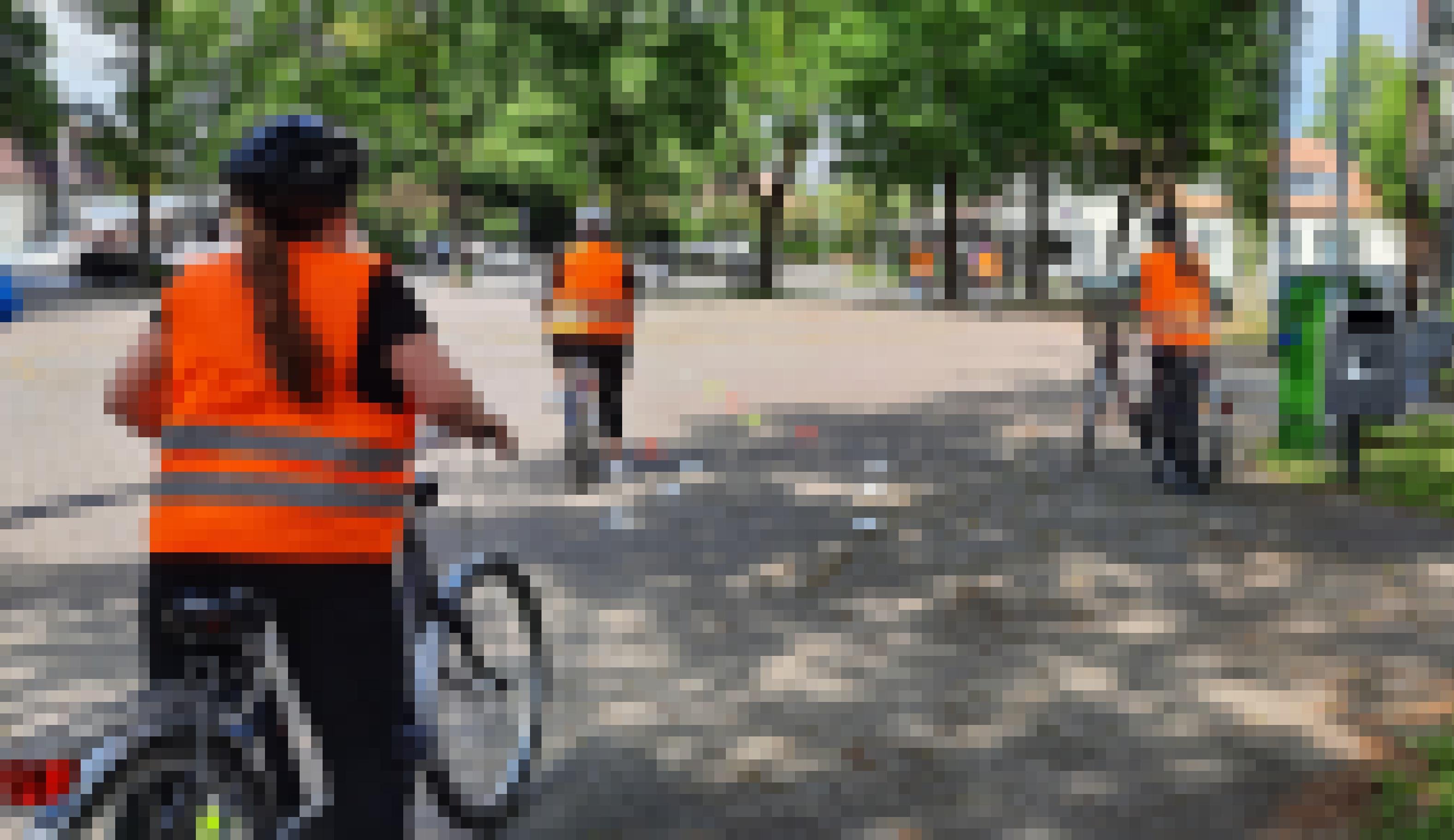 Frauen stehen mit Fahrrädern auf einem Platz, weitere Frauen fahren auf dem Platz Fahrrad. Alle tragen Warnwesten.