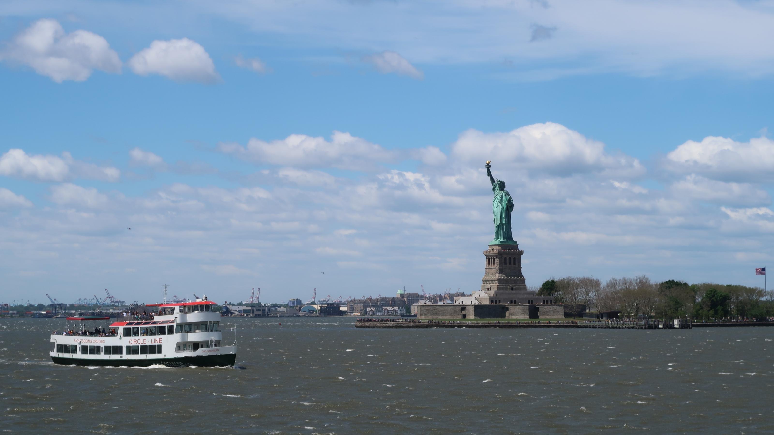 Vor der Freiheitsstatue in New York fährt ein Schiff