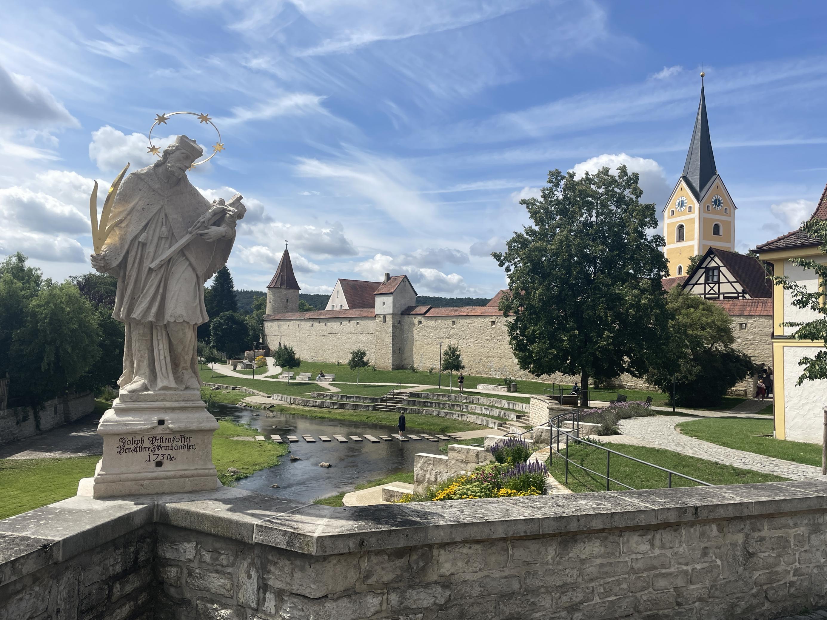 Historische Stadtmauer mit Kirche und Fluss.