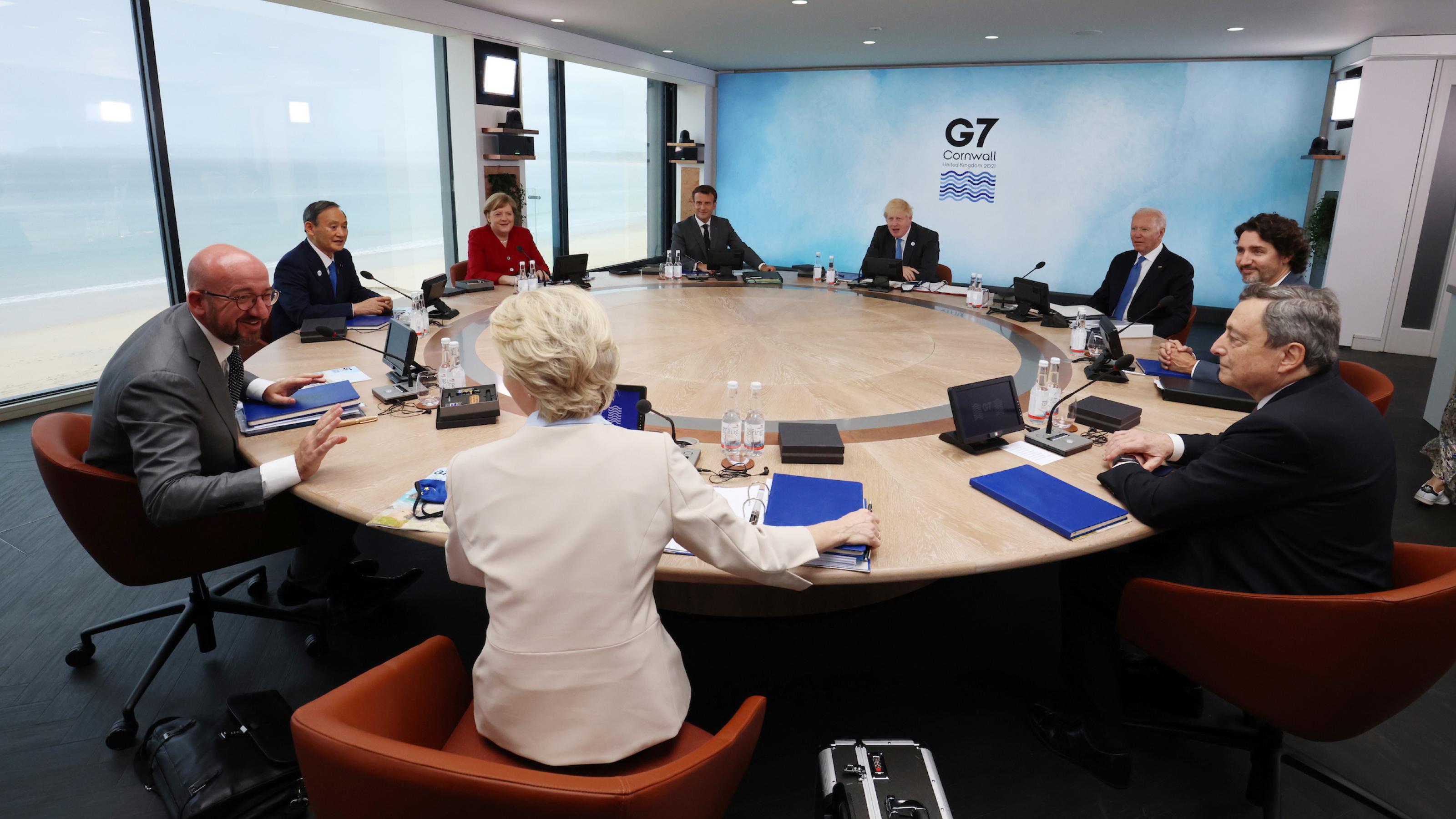 Die Regierungschefs der G7 an einem runden Tisch, hinter ihnen das Meer.
