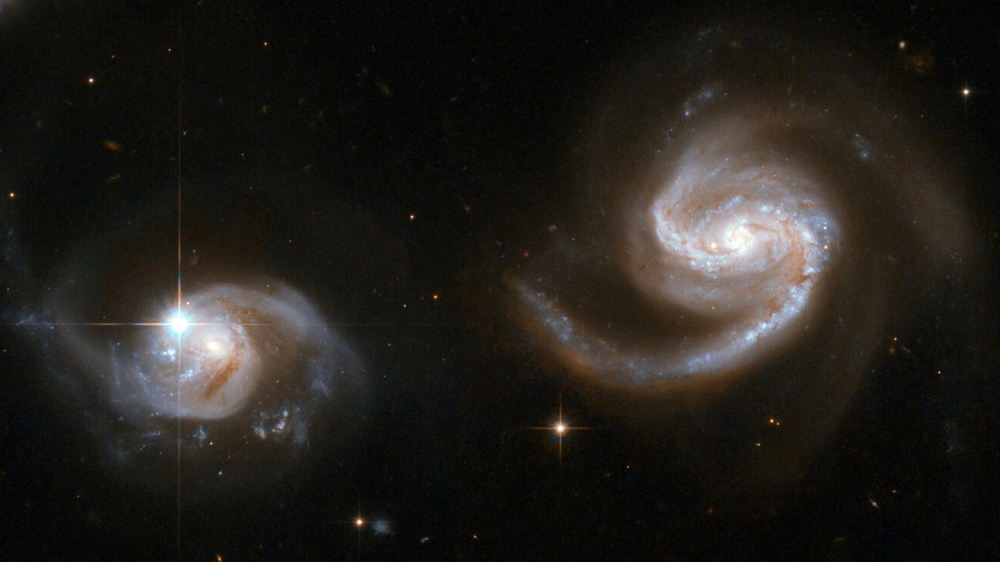 Zwei Spiralgalaxien befinden sich nahe beieinander. Ihre Spiralarme scheinen sich jeweils schon nach der anderen Galaxie auszustrecken.