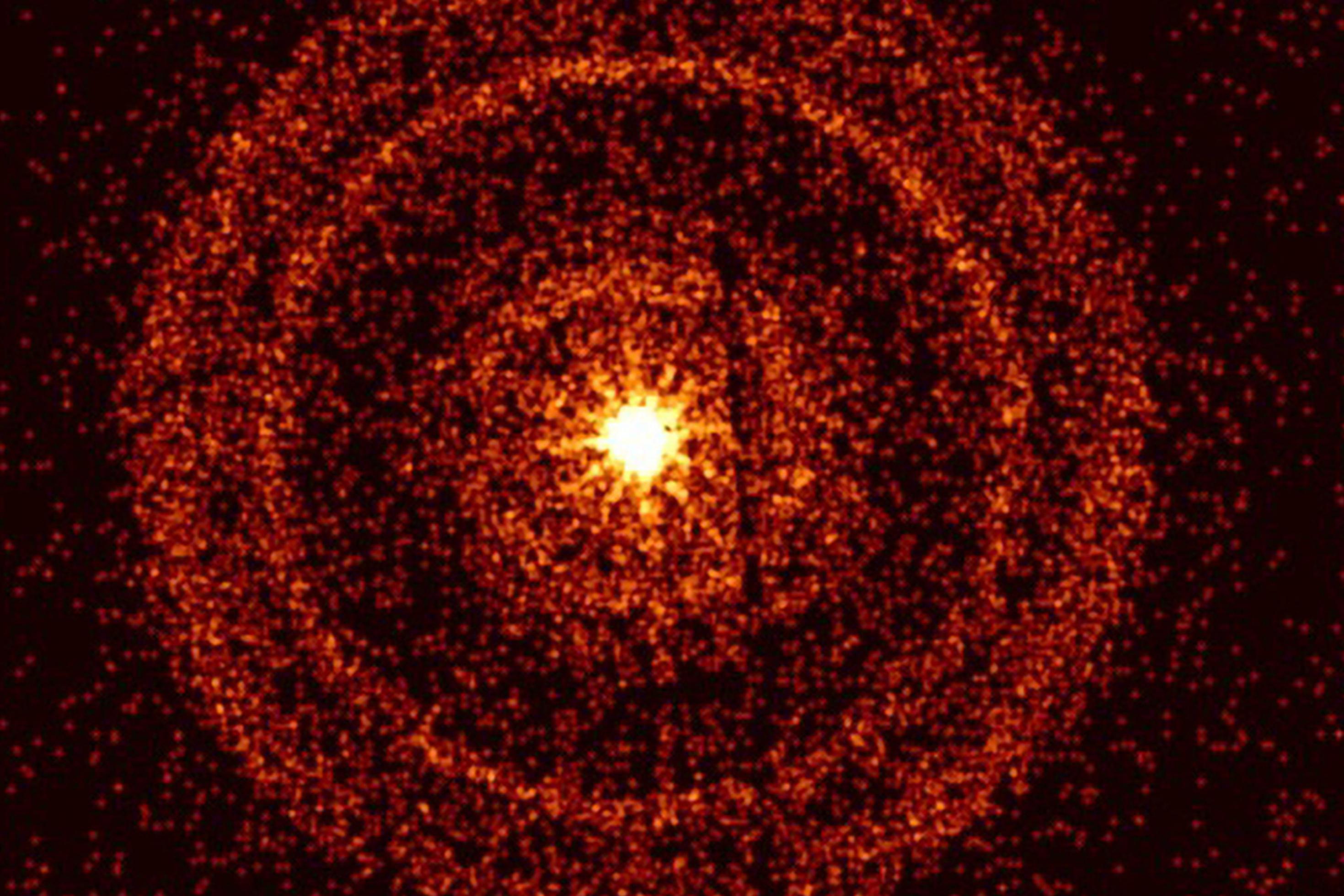 Vor einem schwarzen Hintergrund ist im Zentrum ein orange-gelblicher Kreis zu sehen, umgeben von mehreren konzentrischen Ringen, die ebenfalls orange-gelblich eingefärbt sind und deren Dichte nach außen hin abnimmt.