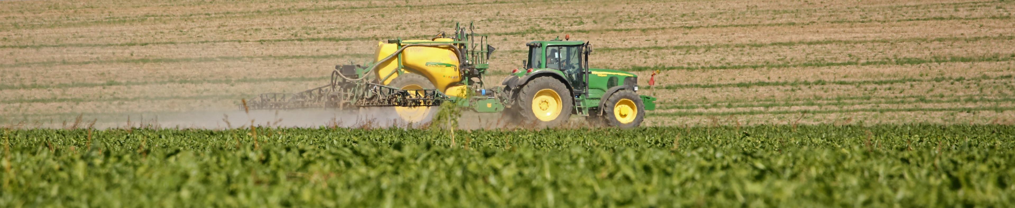 Ein Landwirt versprüht mit seinem Traktor Pestizide auf einem Acker.