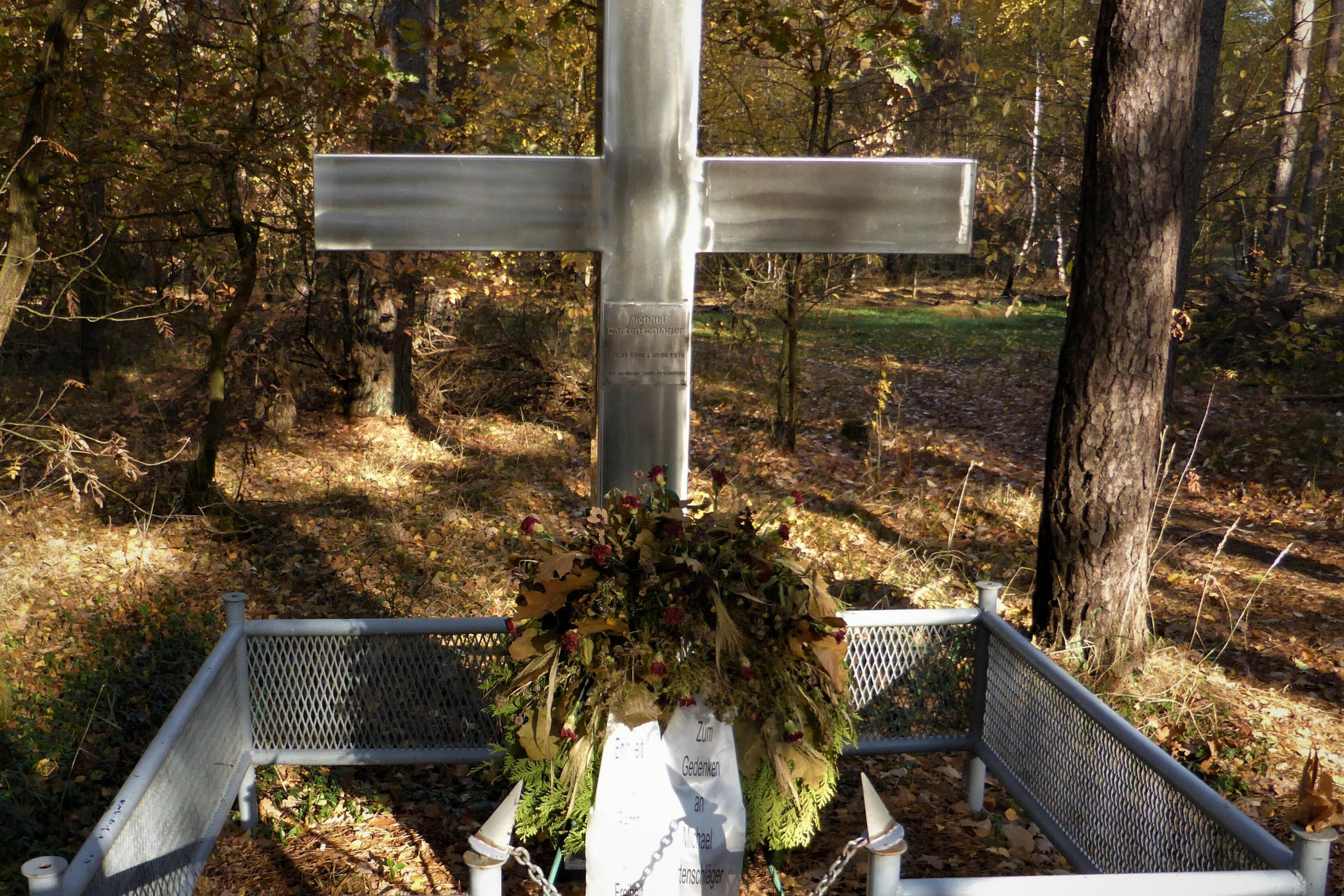 Mit hellem Blech ummanteltes, mannshohes Kreuz zu Ehren von Gartenschläger, inmitten des herbstlichen Waldes zwischen dem holsteinischen Büchen und dem mecklenburgischen Leisterförde.