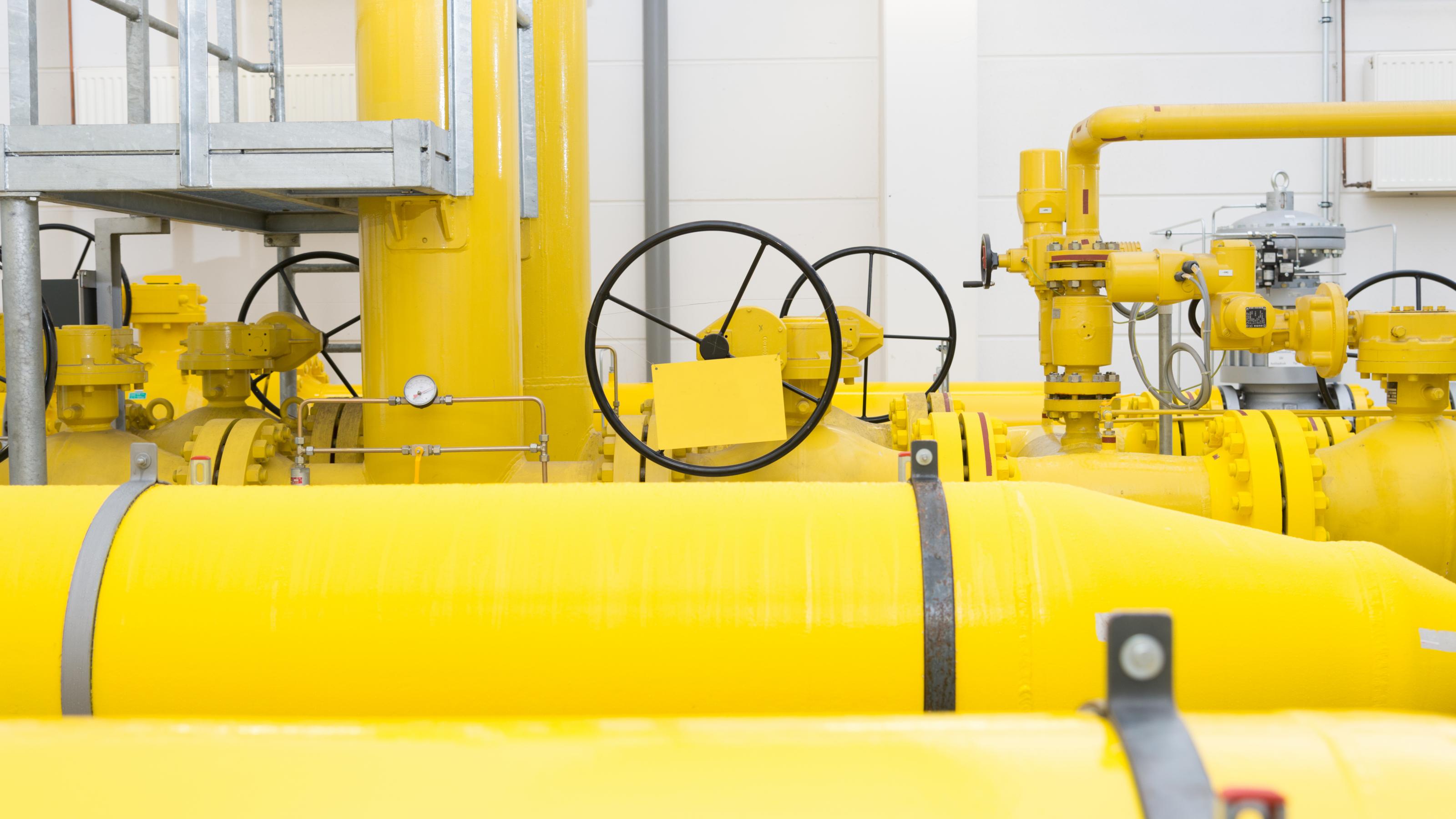 Vier Abschnitt großer, gelb lackierter Pipelines im Innern eines Gebäudes.