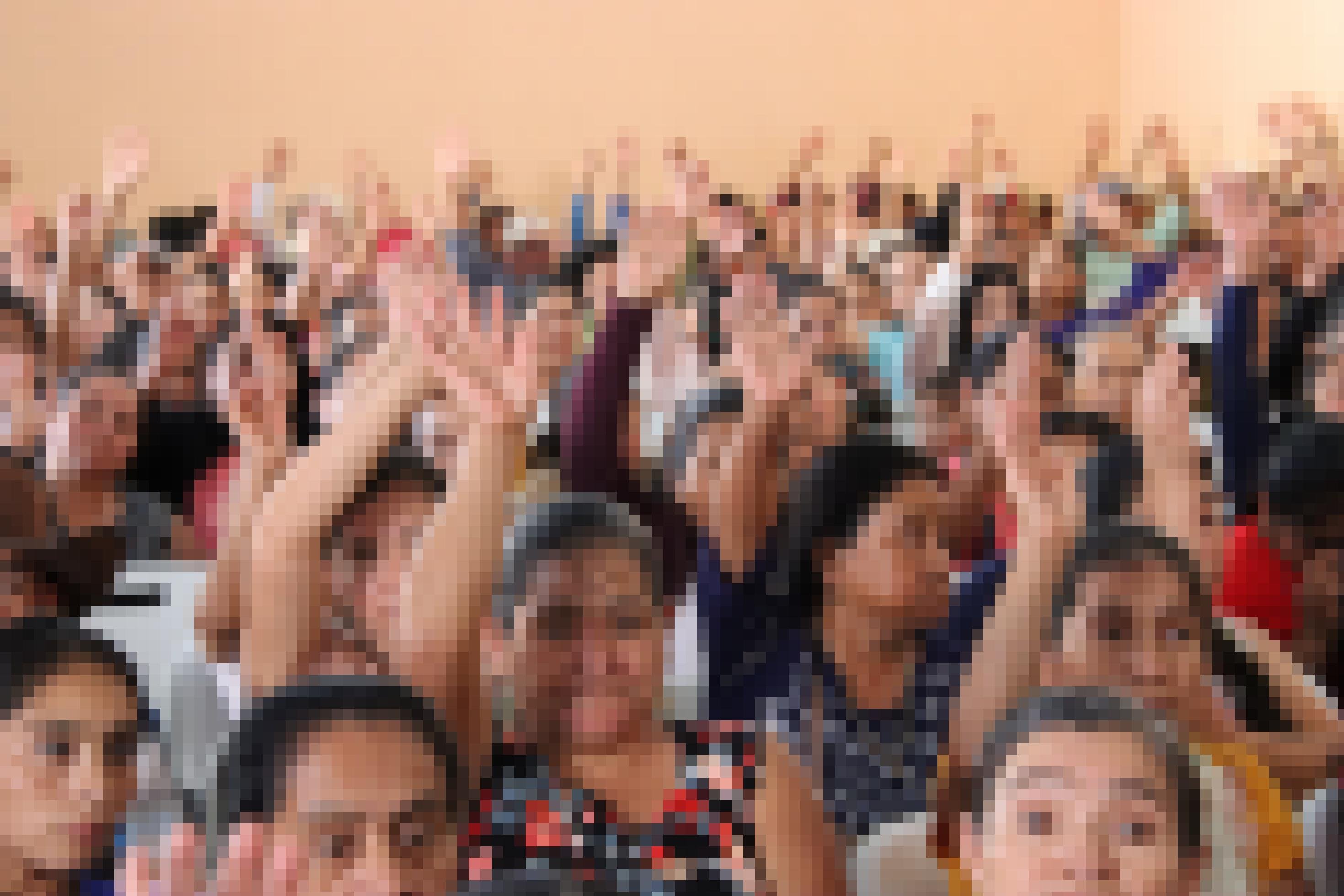 Mehrere Frauen heben die Hände auf einer Versammlung von Kleinbauern in Guatemala.