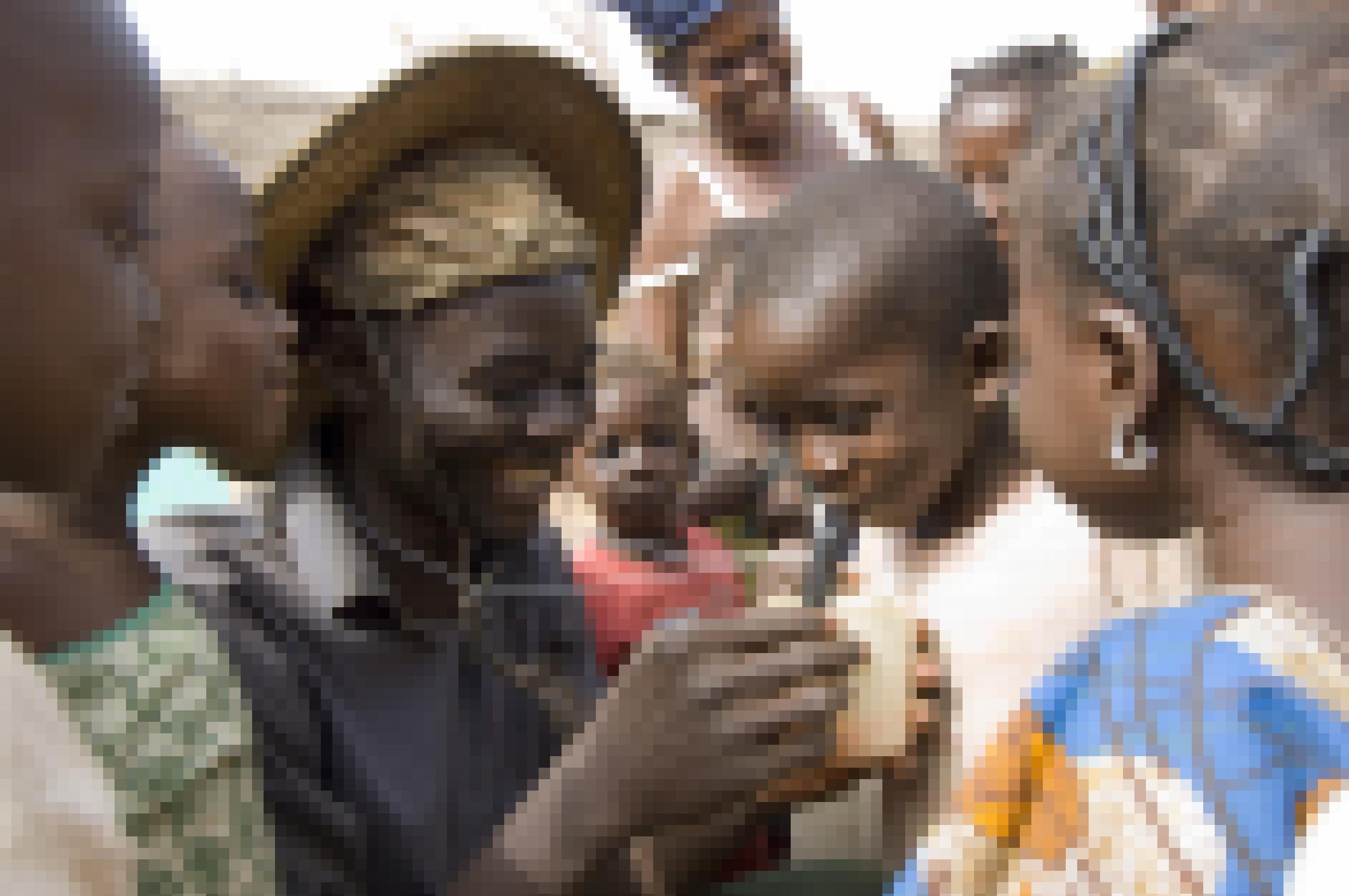 Eine Gruppe von Kindern in Ghana. Ein Mann lässt einen Jungen demonstrieren, wie er mit einem Metallhalm Wasser trinkt. Auf diese Weise werden infizierte Krebstierchen ausgefiltert.