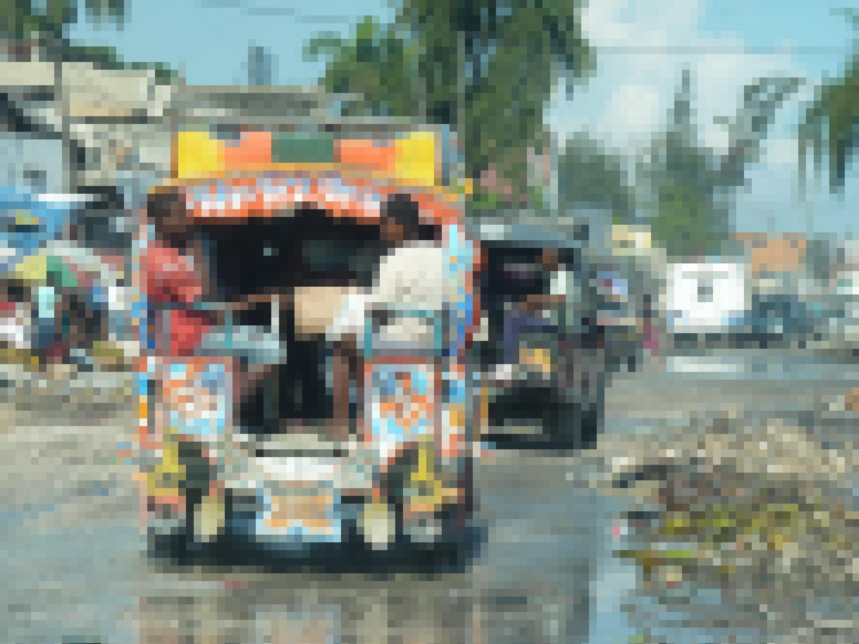 Ein vollbesetzter bunter Kleinbus fährt durch Pfützen und Müllberge in der haitianischen Hauptstadt Port-au-Prince