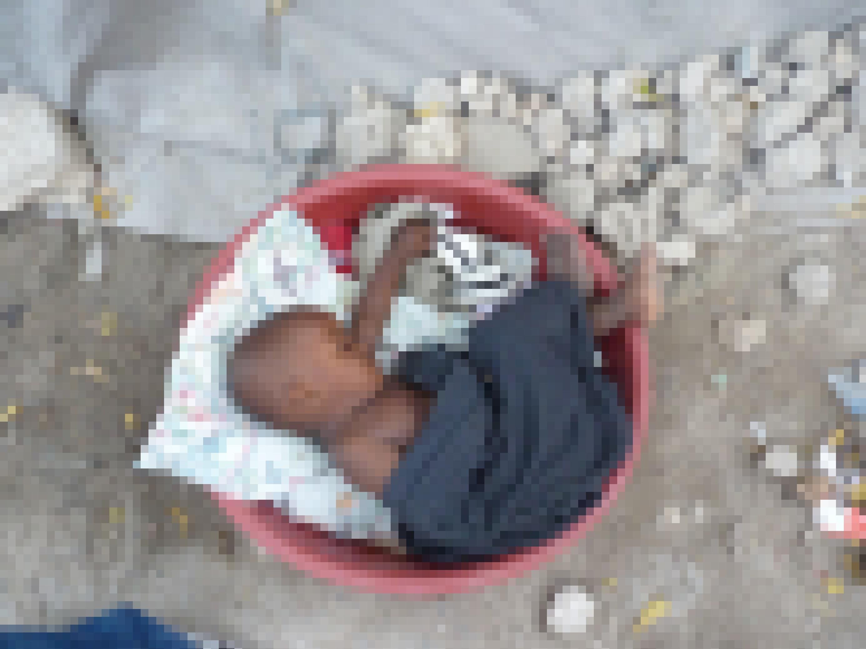 Ein Baby schläft eingerollt in einer runden Plastikschüssel in einem Flüchtlingslager in Haiti.