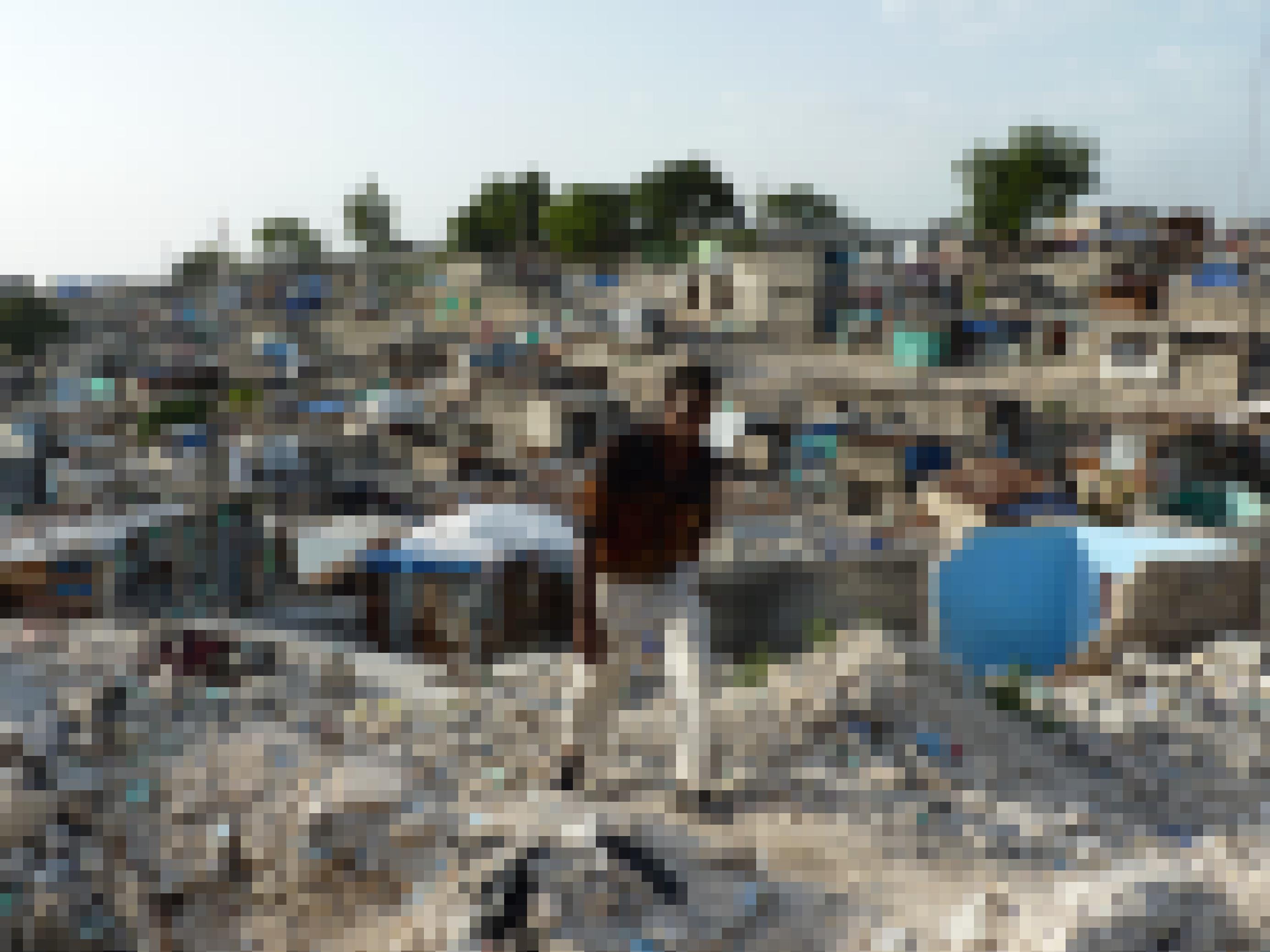 Ein hagerer Haitianer bahnt sich seinen Weg durch Trümmer, im Hintergrund zerstörte Häuser in Haitis Hauptstadt Port-au-Prince