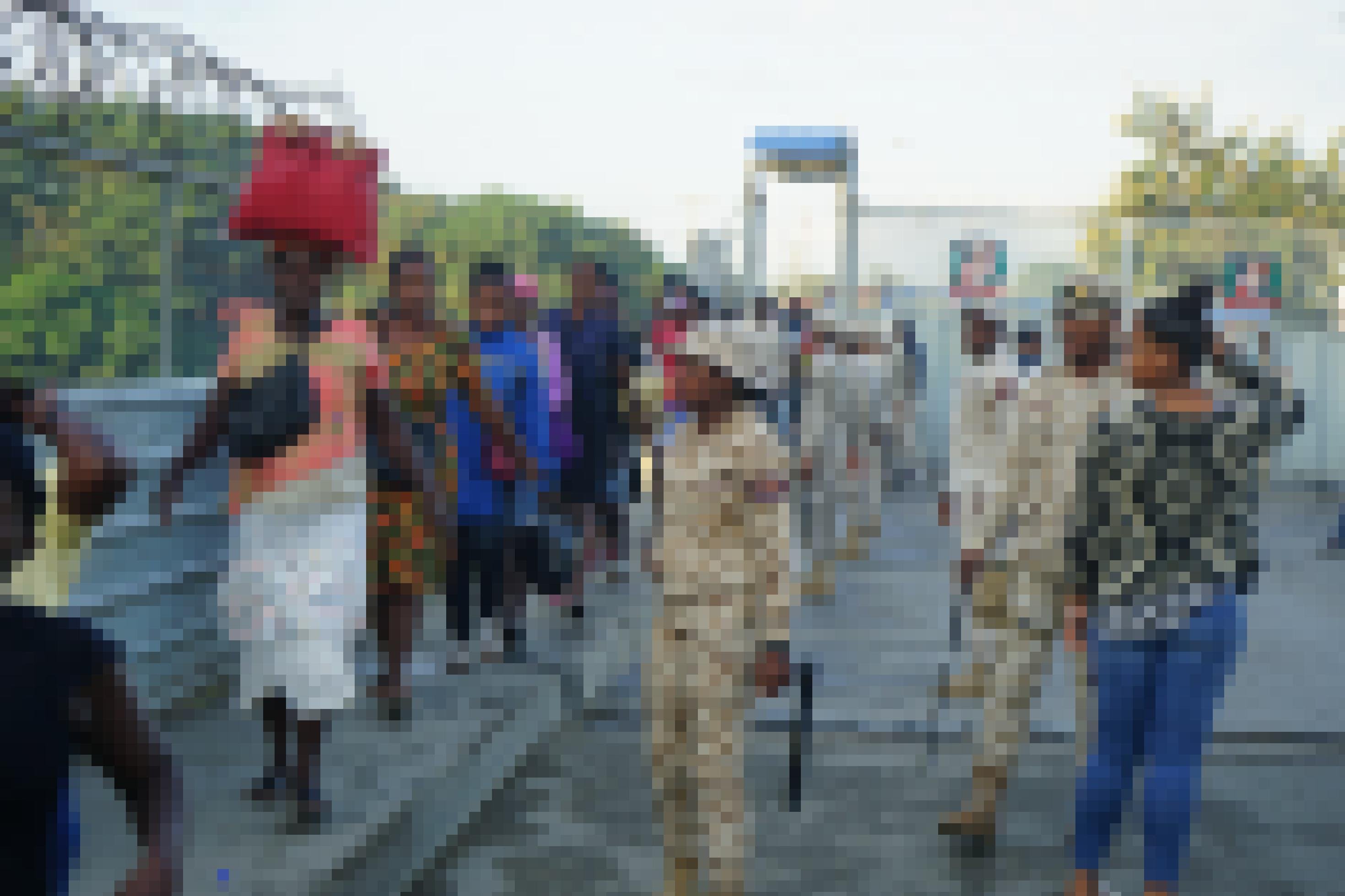 Grenzschützer in hellen Uniformen überwachen die haitianischen Tagesmigranten, die im Gänsemarsch über die Grenzbrücke kommen.