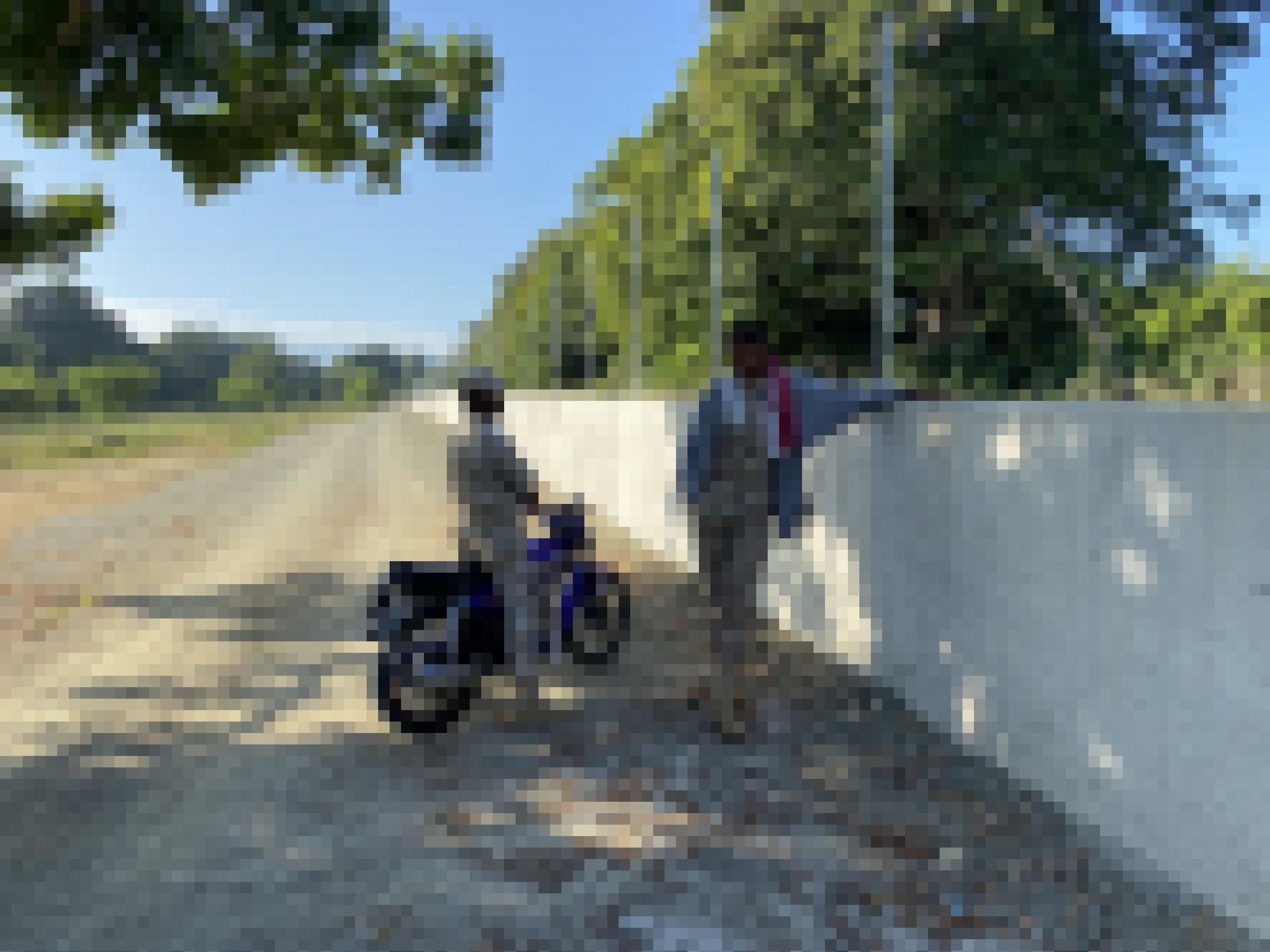 Ein Grenzschützer in heller Uniform auf einem Motorrad und ein stehender Grenzschützer an einer etwa 1 Meter hohen Grenzmauer aus Beton