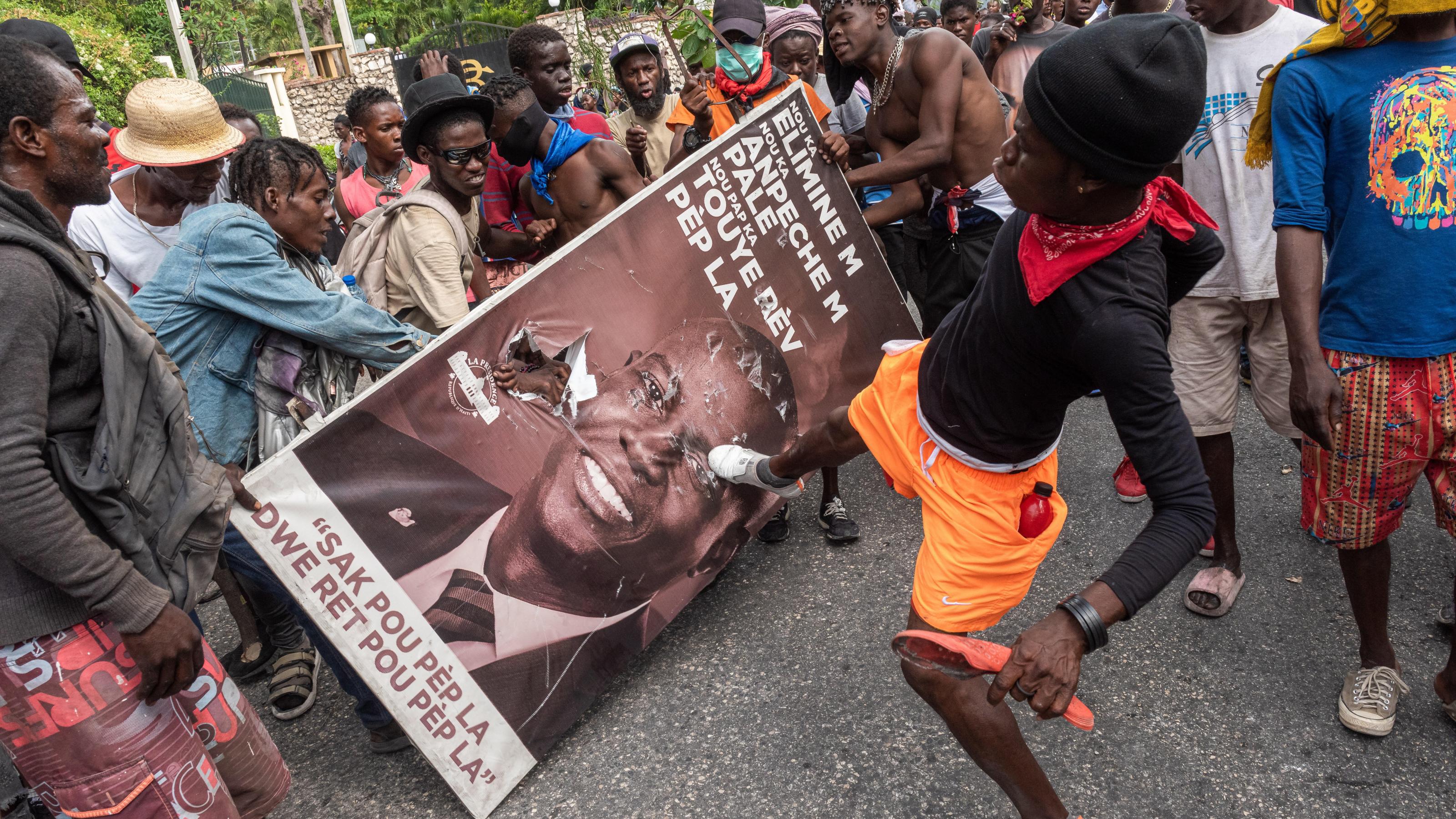 Protesters damage a poster with the image of assassinated president Jovenel Moise during a demonstration against authorities' inaction against criminal gangs, in Port-au-Prince, Haiti, 30 March 2022. The mobilization, preceded yesterday by the largest demonstration in the country since the assassination of President Jovenel Moise, was called by numerous associations and political and civil society organizations to express their weariness with the inaction of the Government and of the police in the fight against the criminality of armed gangs, which control important neighborhoods in the capital. Photo: picture alliance/EPA/Johnson Sabin