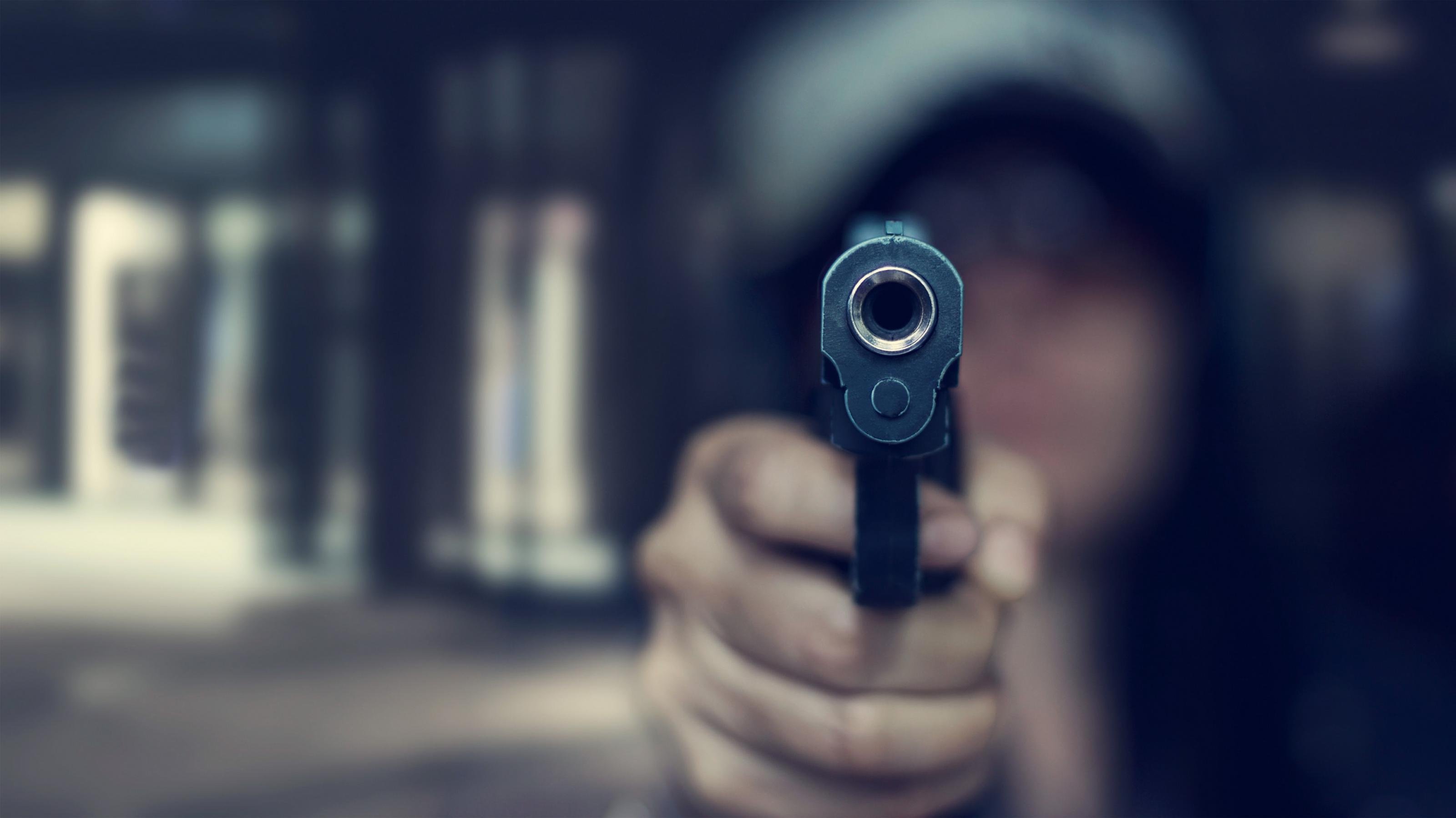 Eine Frau zielt mit einer Pistole auf den Betrachter.