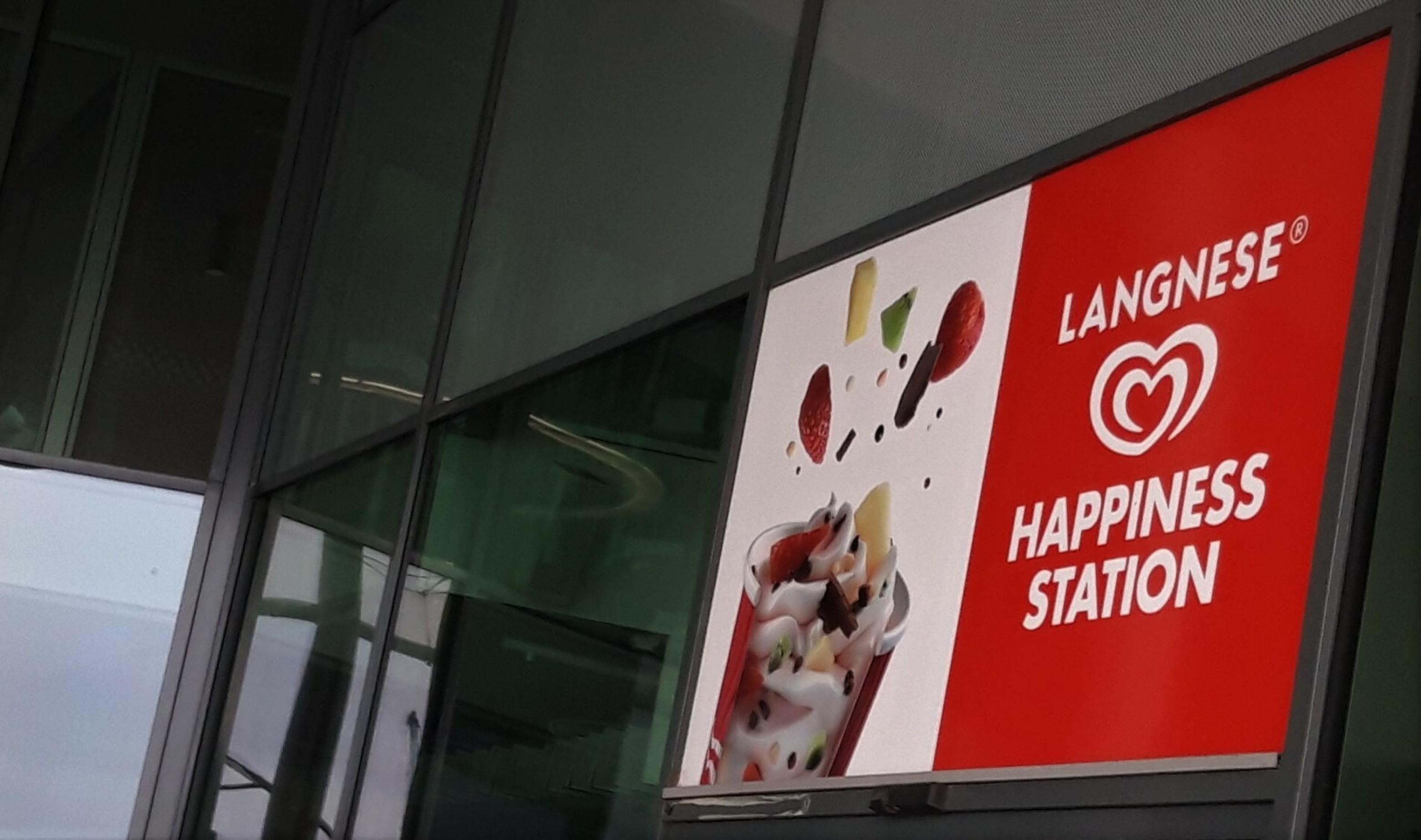 Eine bunte Tafel wirbt für die „Langnese-Happiness-Station“.