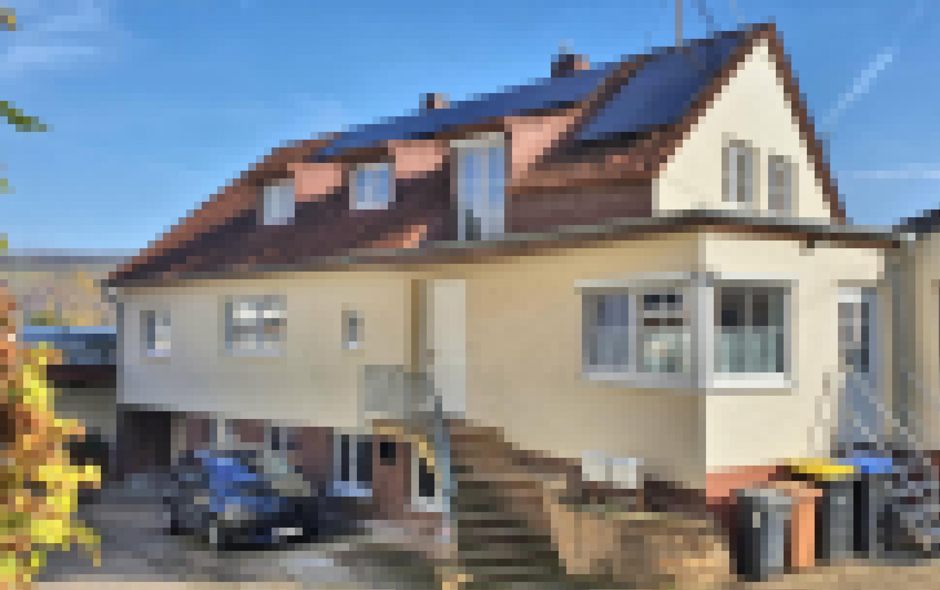 Ein Elektroauto steht vor einem Haus, auf dessen Dach sich Solarzellen befinden.