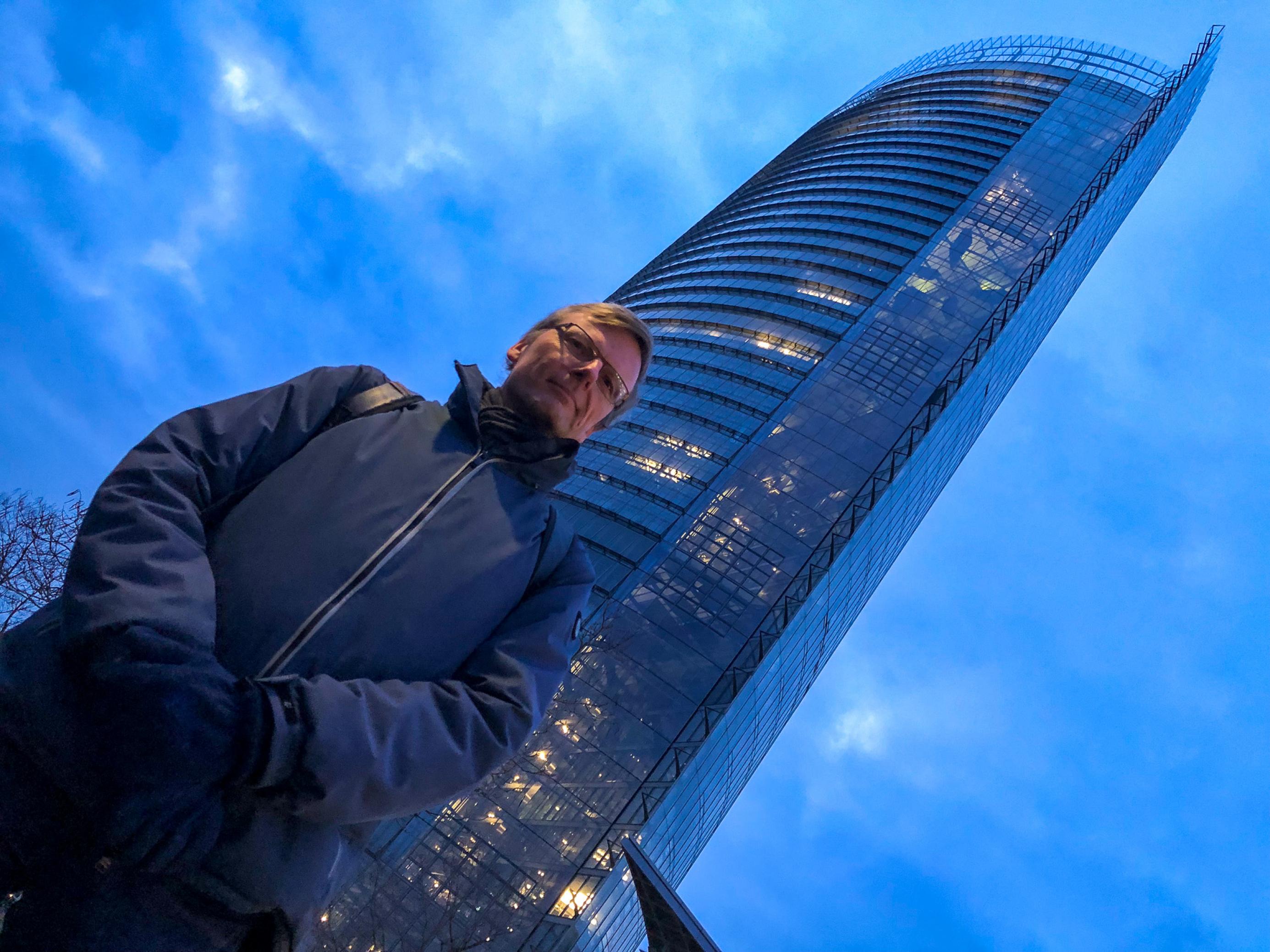 Ein Mann in Winterjacke steht vor dem Post-Tower.