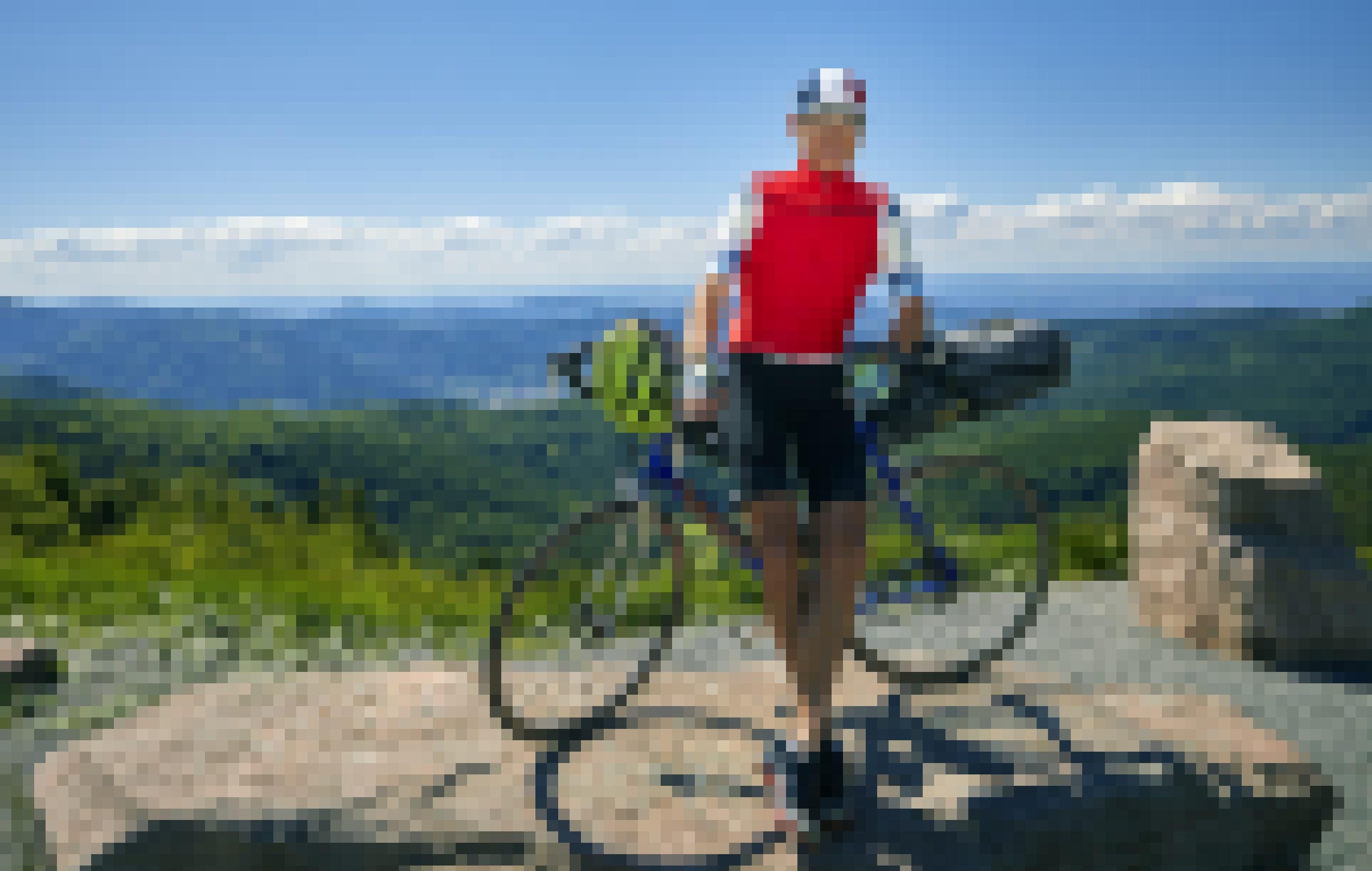 Der Reporter posiert mit seinem Rennrad unter strahlend blauem Himmel vor einer aussichtsreichen Berglandschaft.