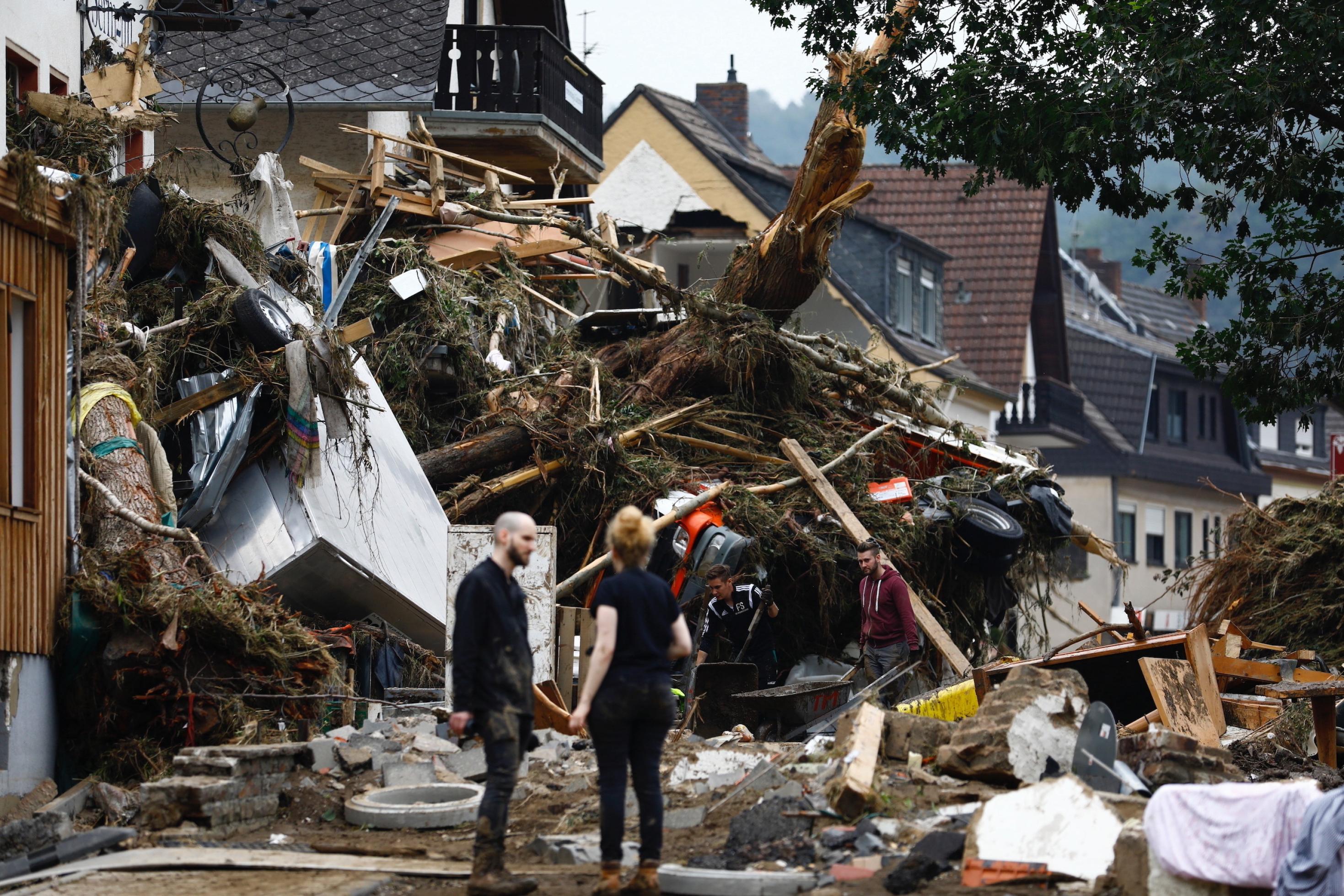 2 junge Menschen stehen vor einem zerstörten Haus