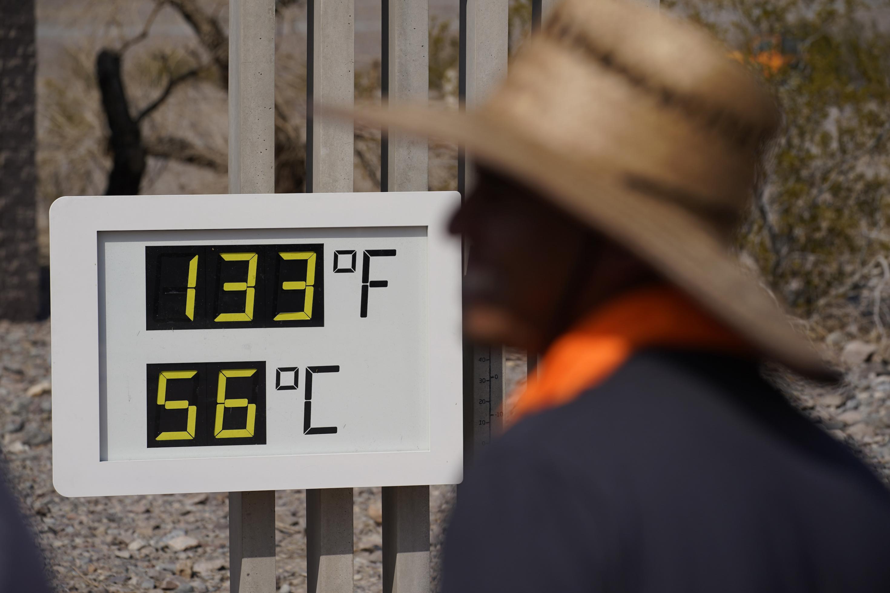 Outdoor-Thermometer zeigt 56 Grad, im Vordergrund ein Mann mit Hut.