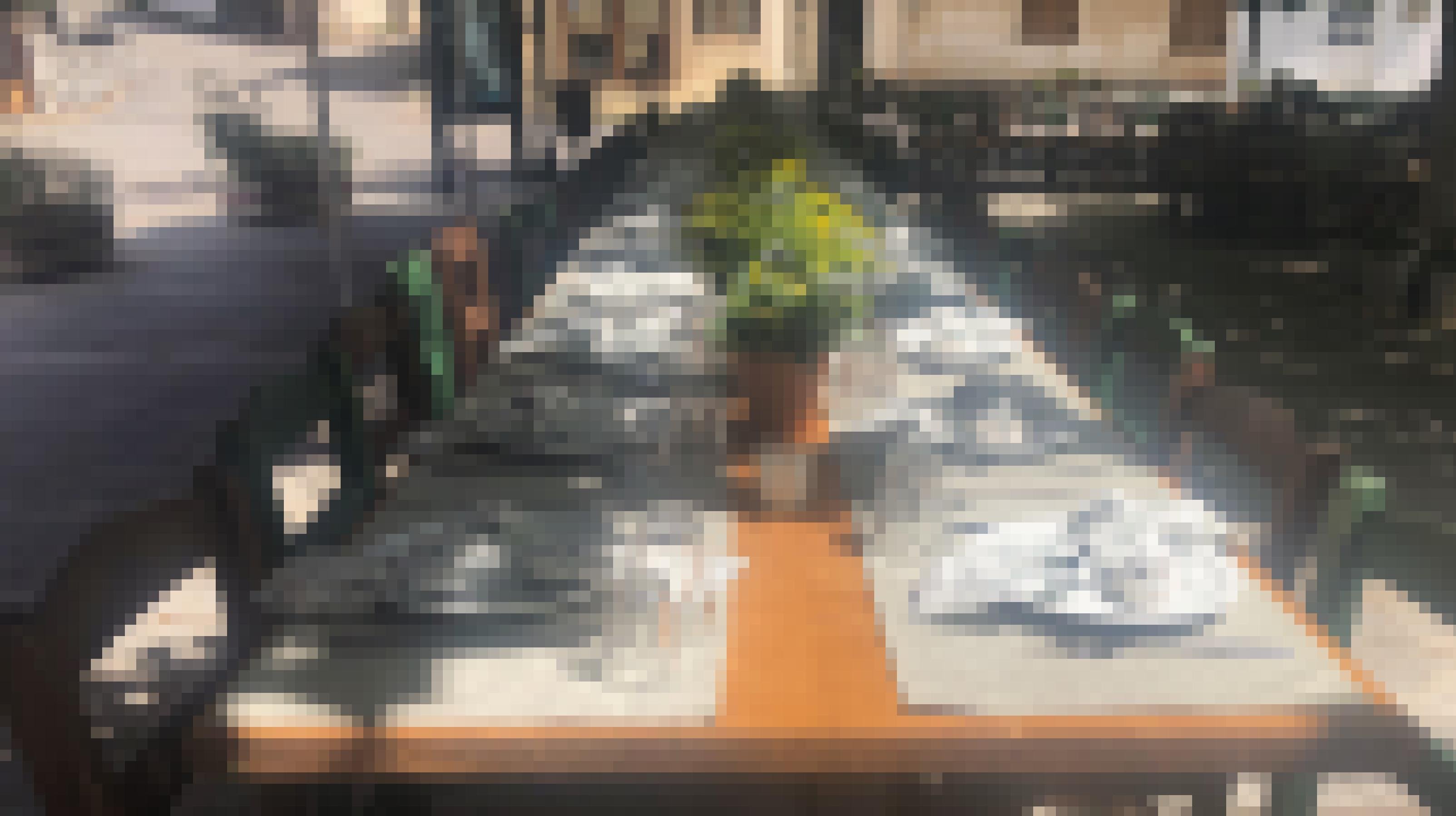 Eine lange Festtafel ist mit Blumen geschmückt und  mit Tellern, Gläsern und Besteck gedeckt.