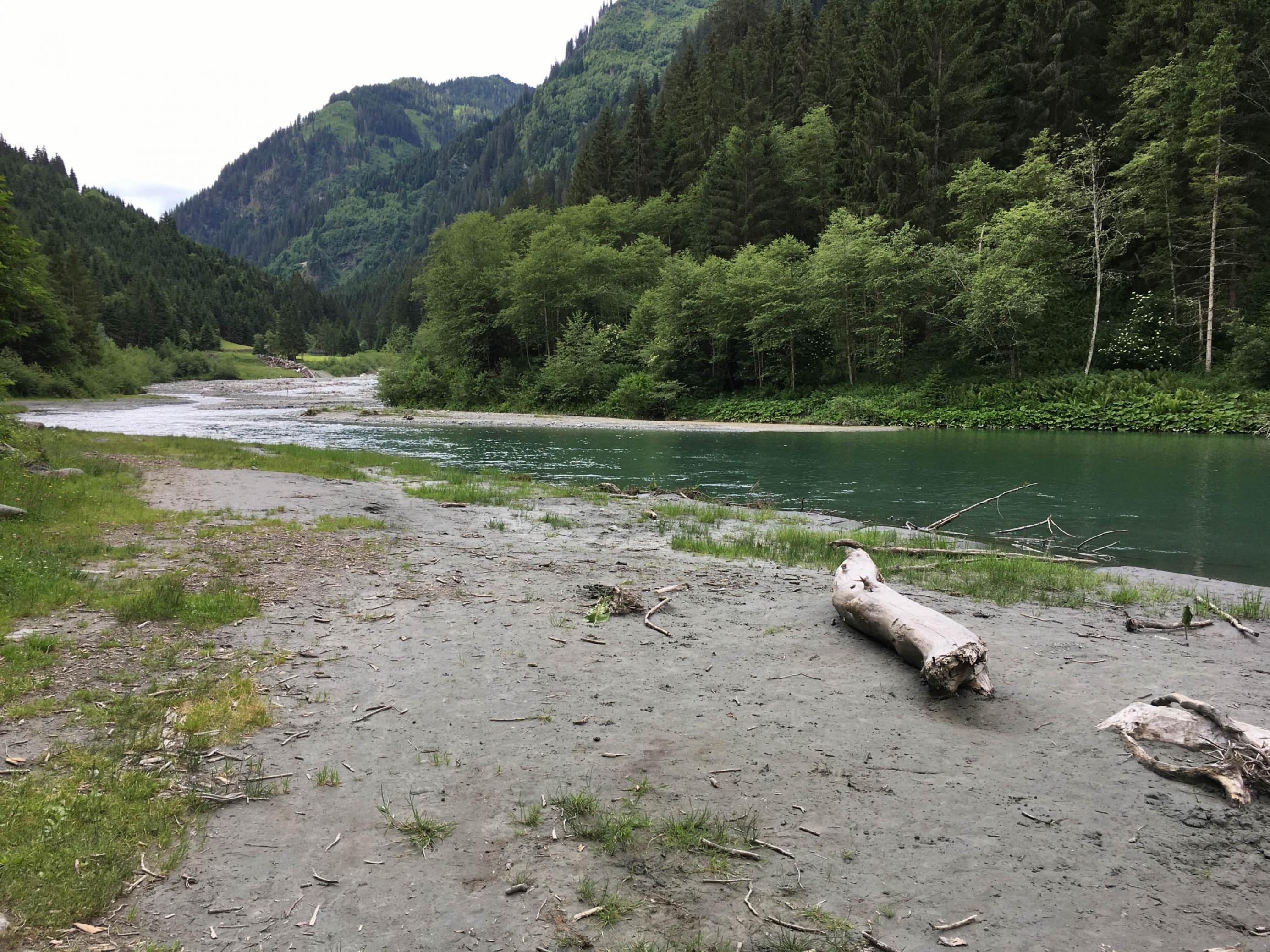 Ruhiger Gebirgsbach, Wald, Berge, Sandstrand im Vordergrund