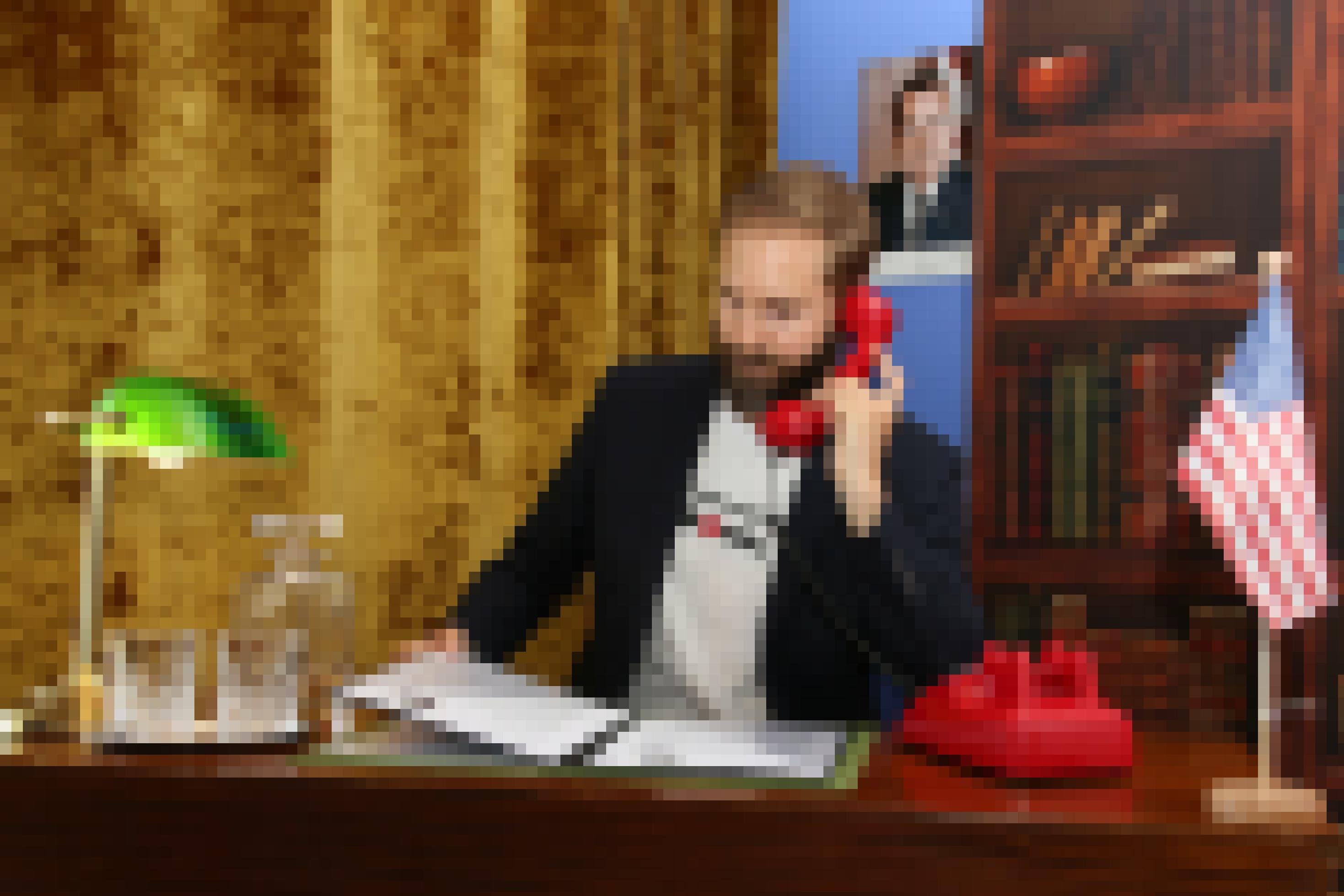 Ein Mann im Jackett sitzt am Schreibtisch und telefoniert.