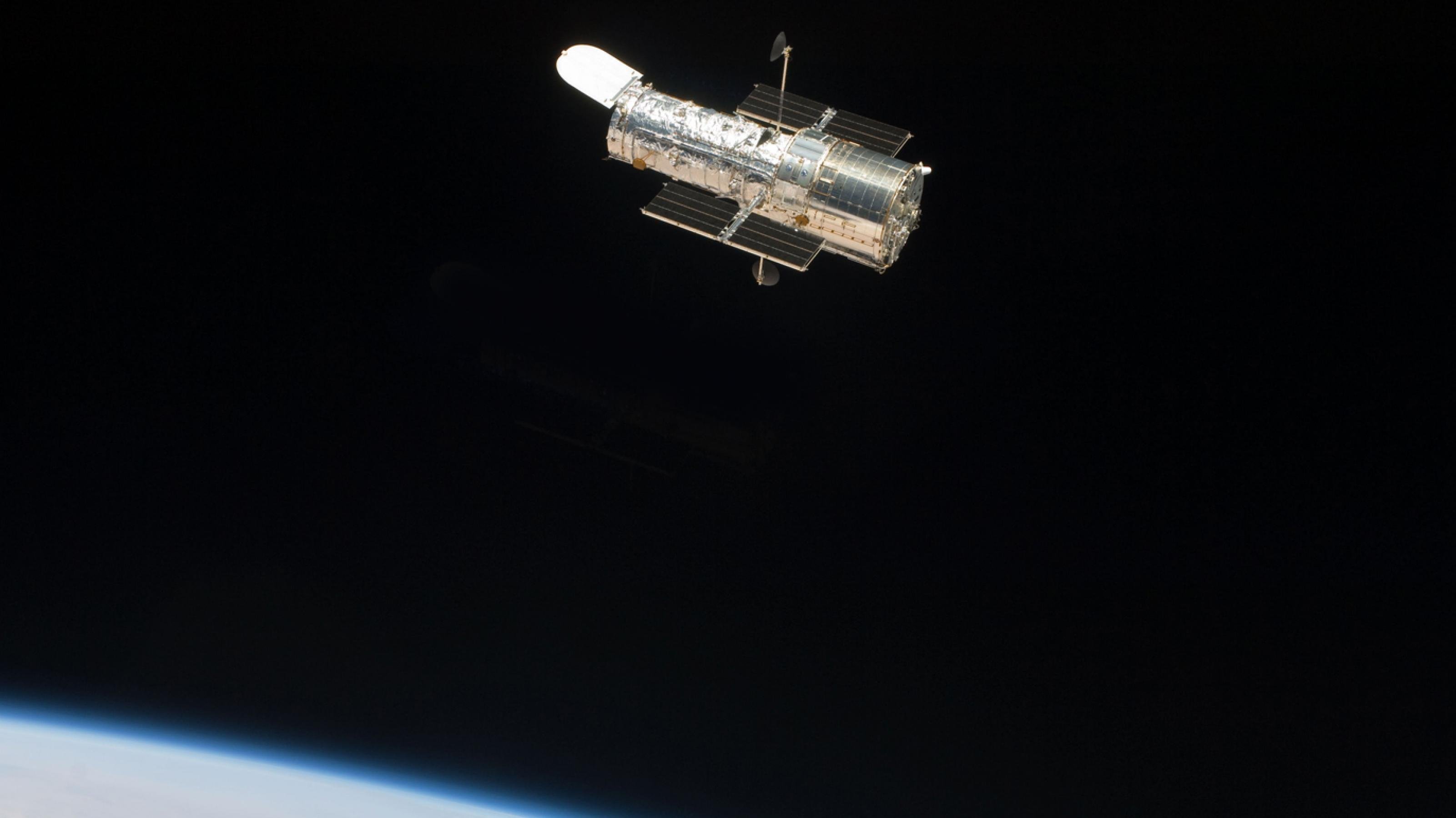 Hubble kreist um die Erde, die blau darunter schimmert