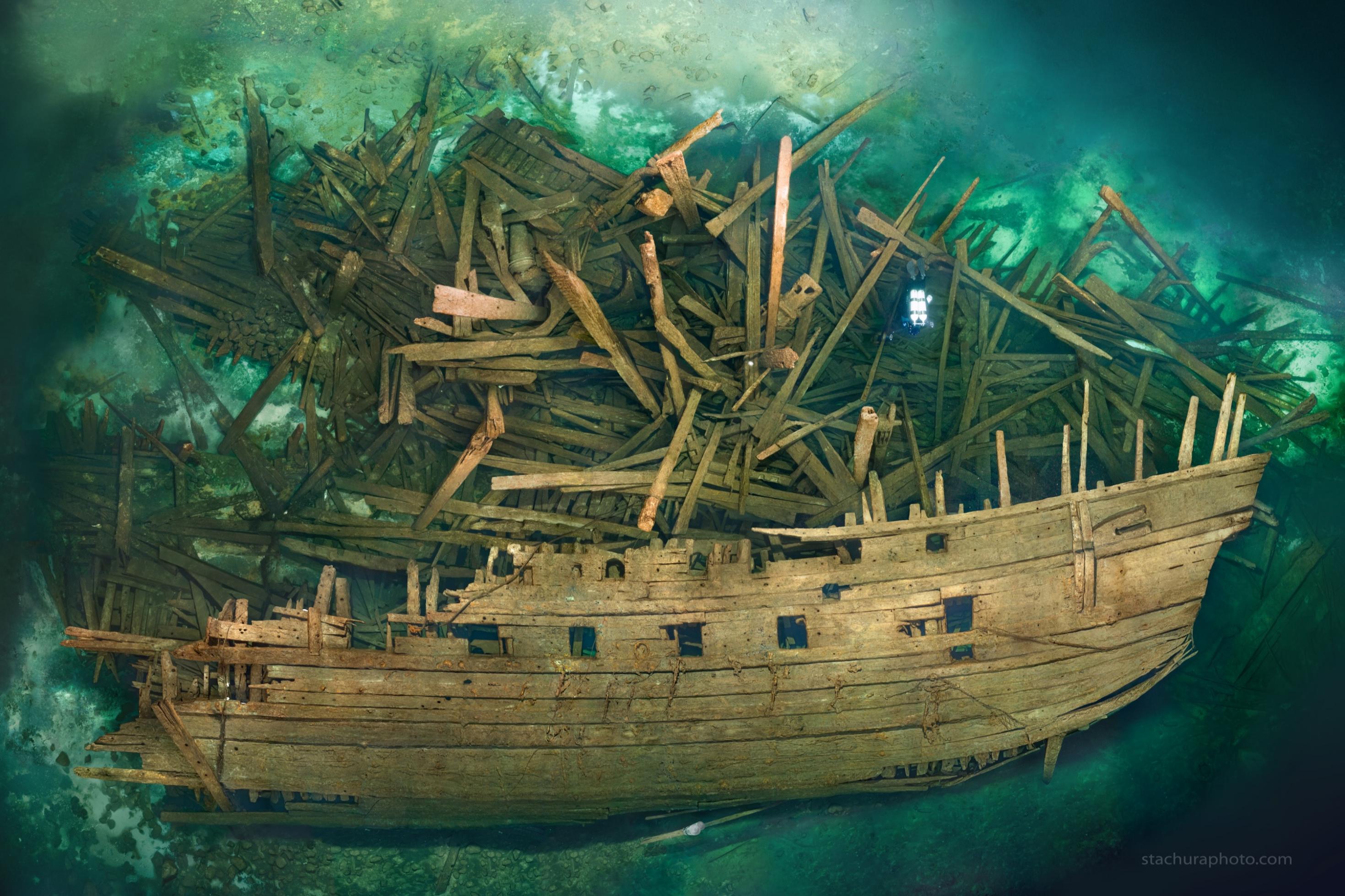 Ein Holzschiff und unzählige lose Planken am Meeresboden von der Seite zu sehen