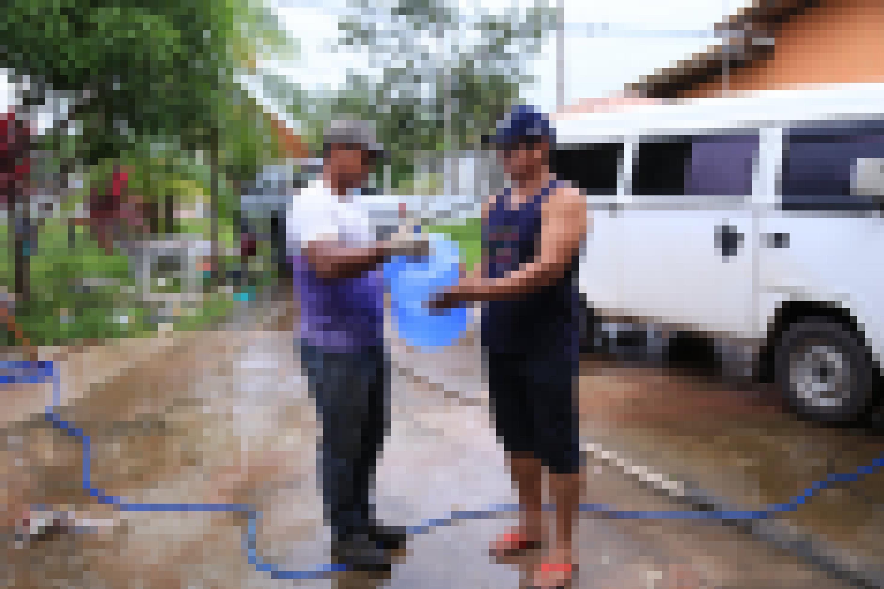Ein Mitarbeiter von Hydro übergibt einem Anwohner eine große Galone mit Trinkwasser.