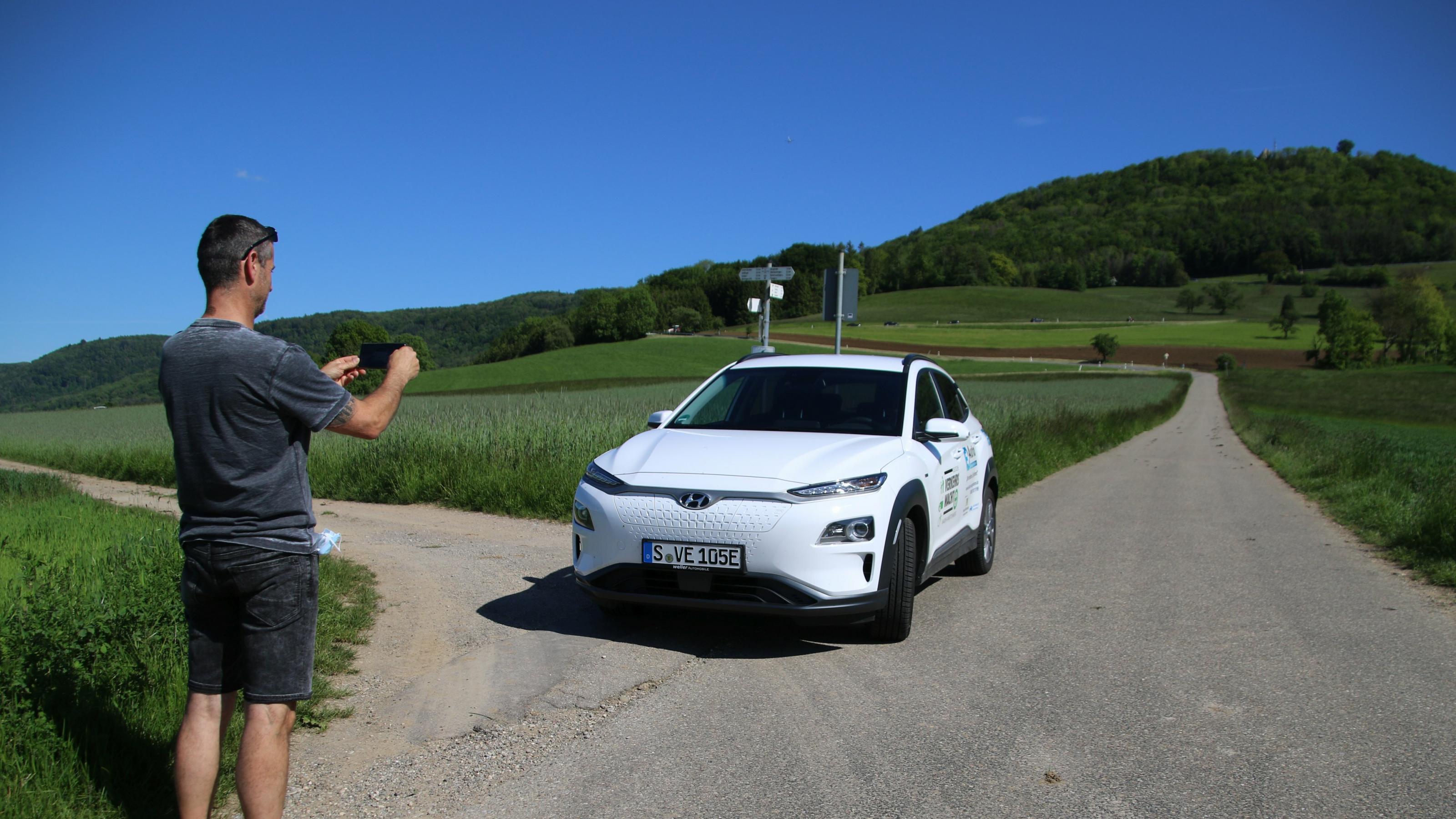 Ein Mann fotografiert mit seinem Handy ein Auto.