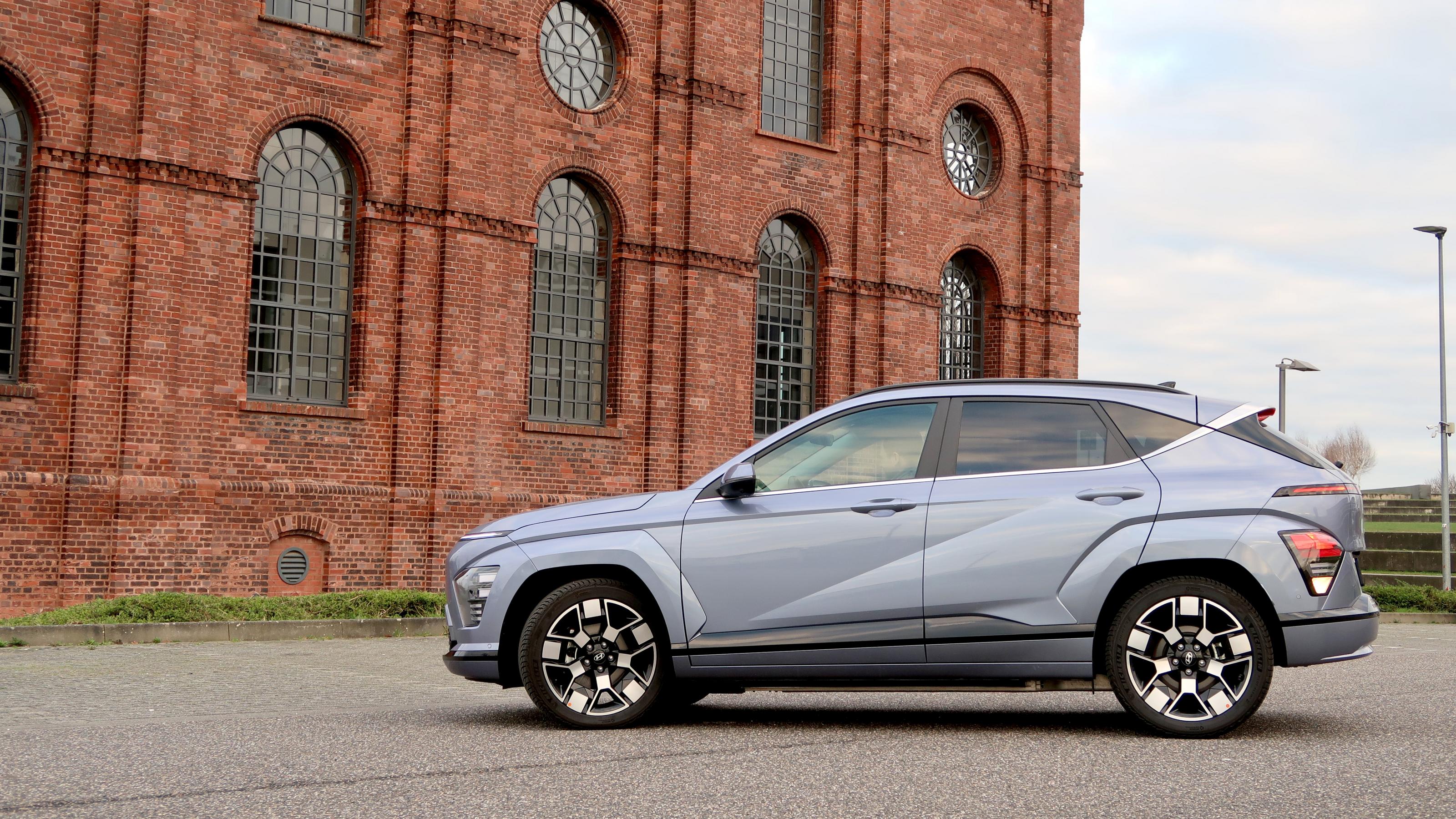 Hyundai Kona steht vor einem backsteinern Fabrikgebäude