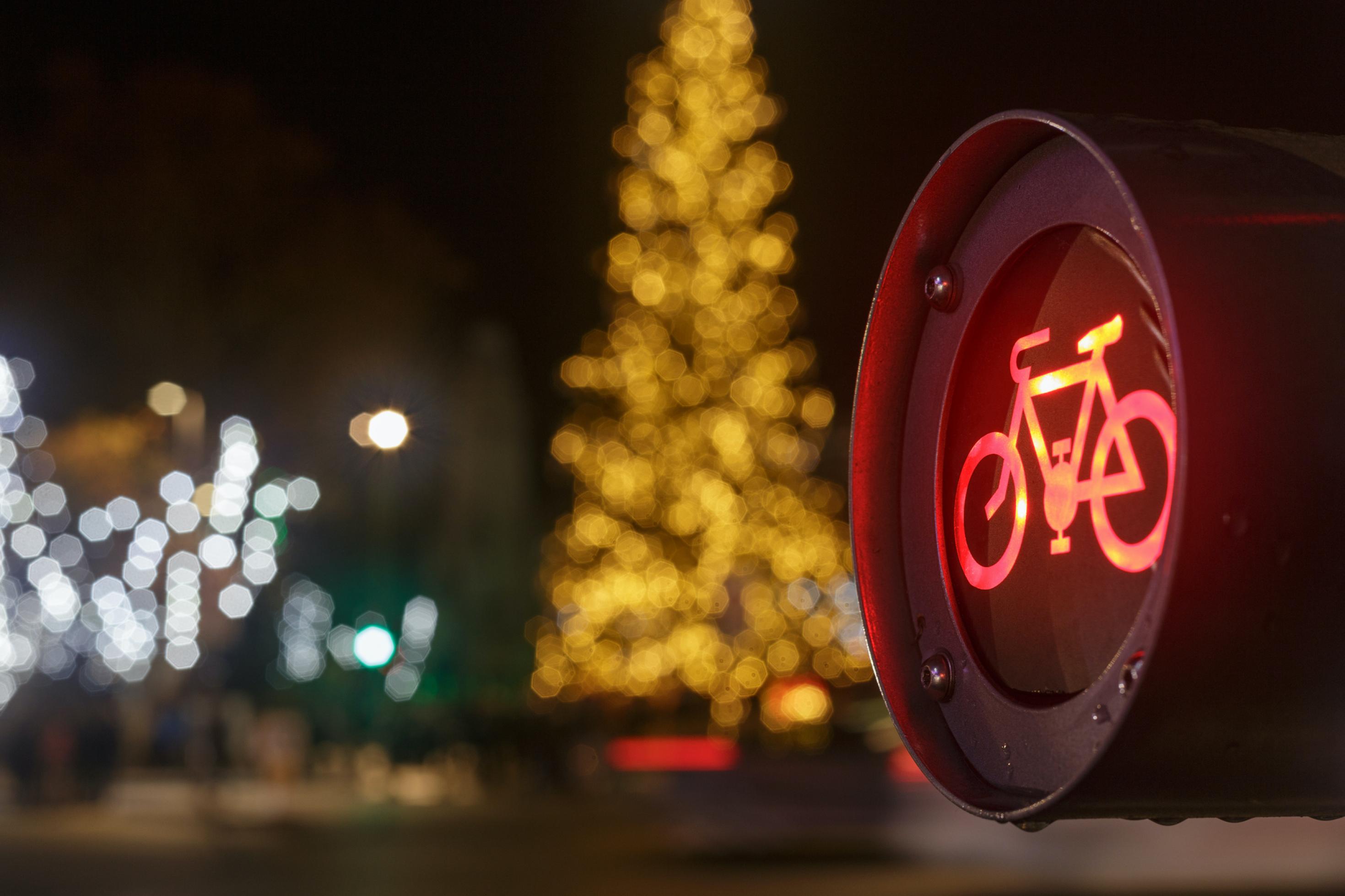 Nahaufnahme einer roten Ampel für Fahrräder mit Weihnachtsdekoration im Hintergrund