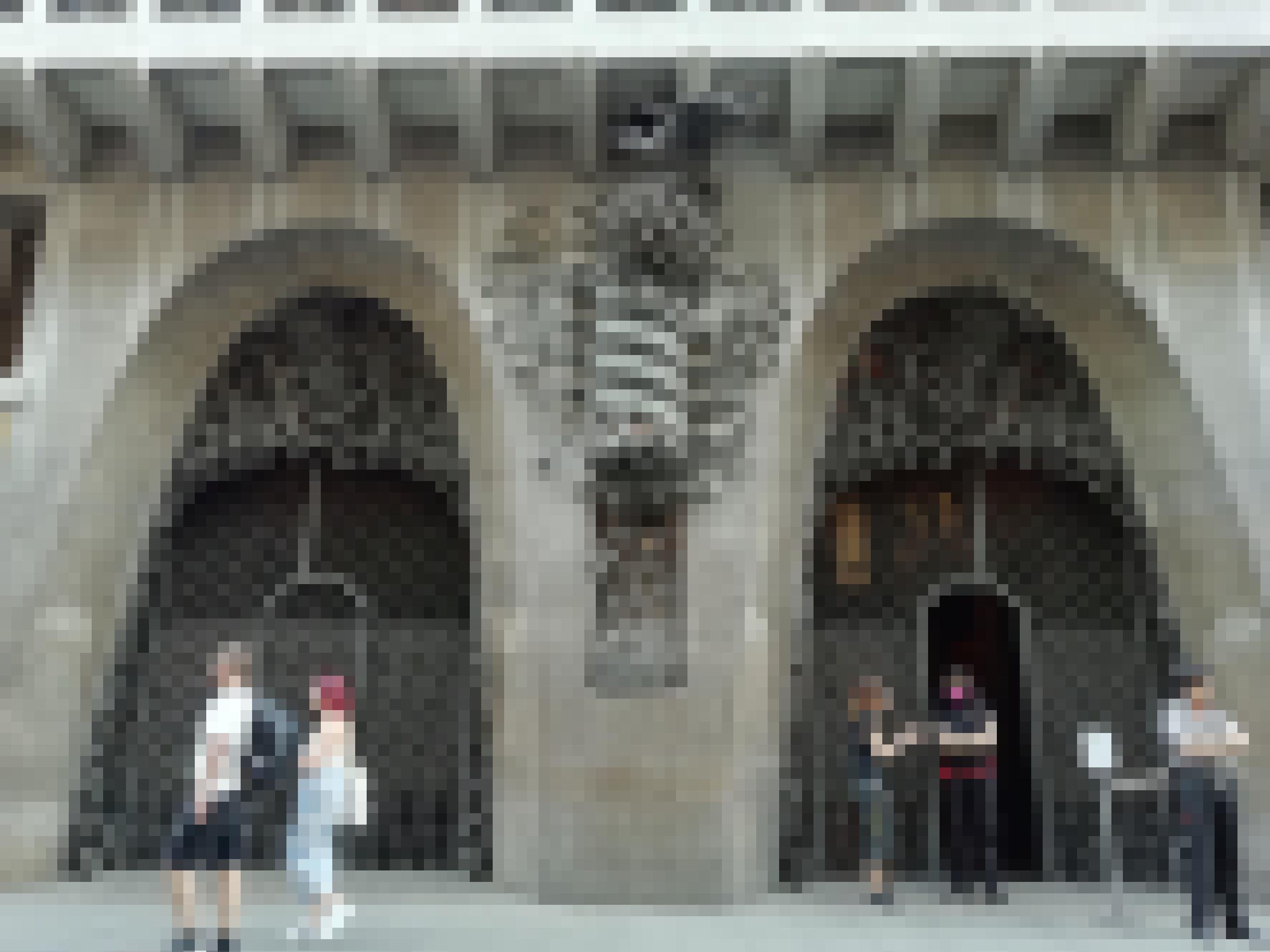 Touristen flanieren vor dem schmiedeeisernen Eisentor des Palau Güell in Barcelona