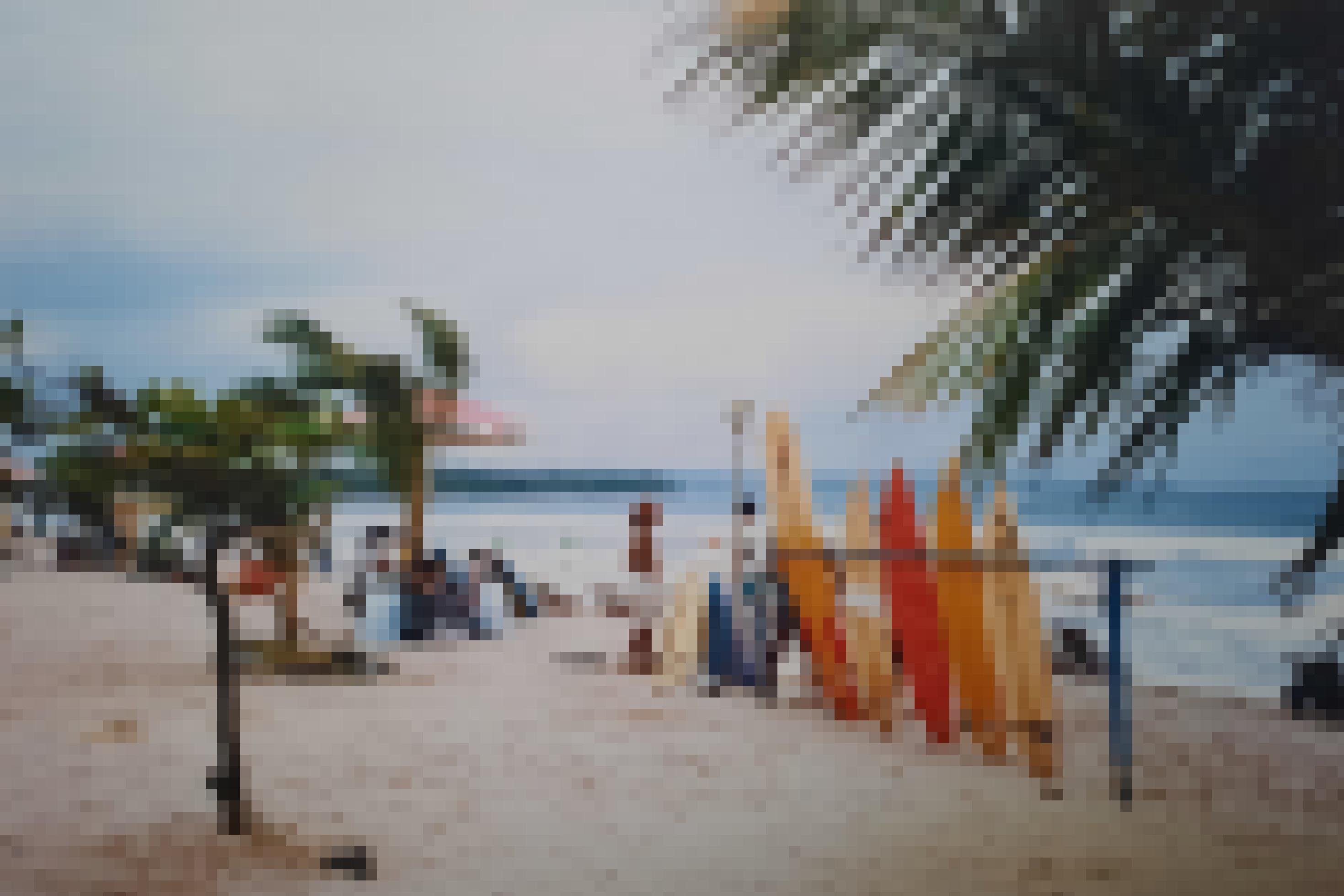 Leerer Strand von Kuta im Süden von Bali: Eine Gruppe Souvenirverkäufer und ein Surfboardverleiher warten auf Kundschaft.