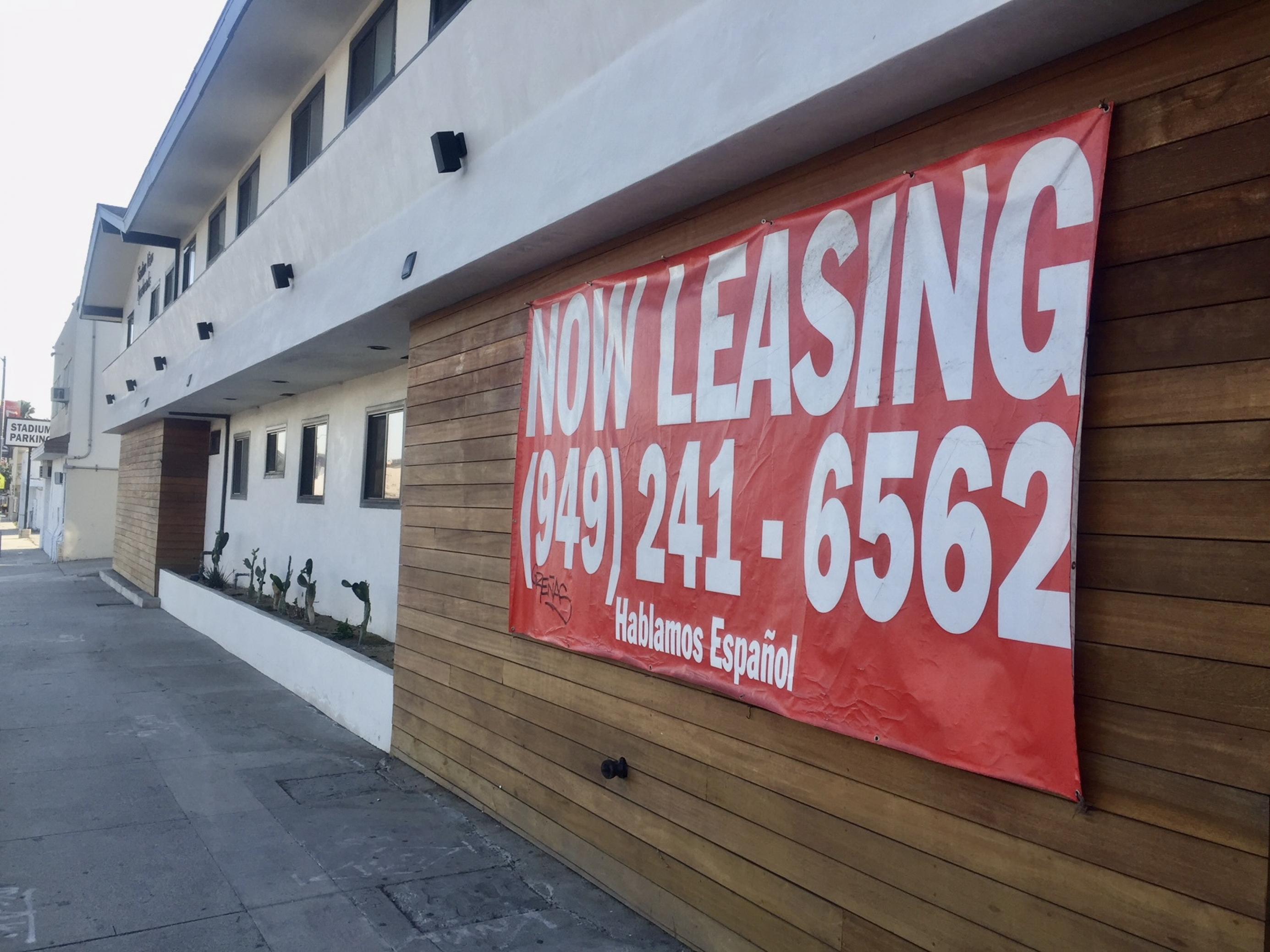 Ein rotes Banner an einem neuen Apartmentgebäude wirbt für Luxuswohnungen in Stadionnähe. Die sind oft zu teuer für Bewohner und Bewohnerinnen, die bisher in Inglewood wohnen.