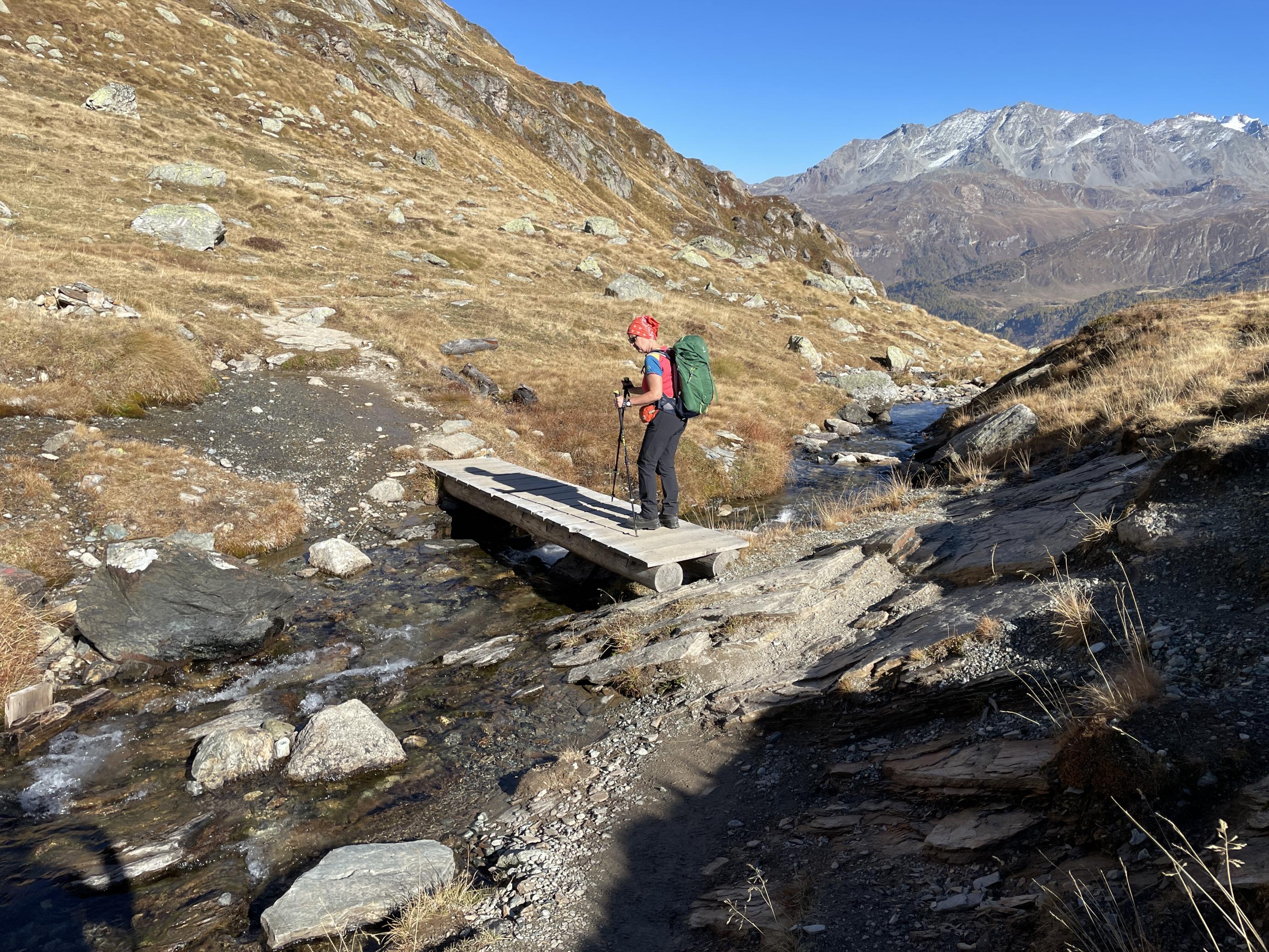 Kleiner Gebirgsbach mit Holzbrücke und Wanderin