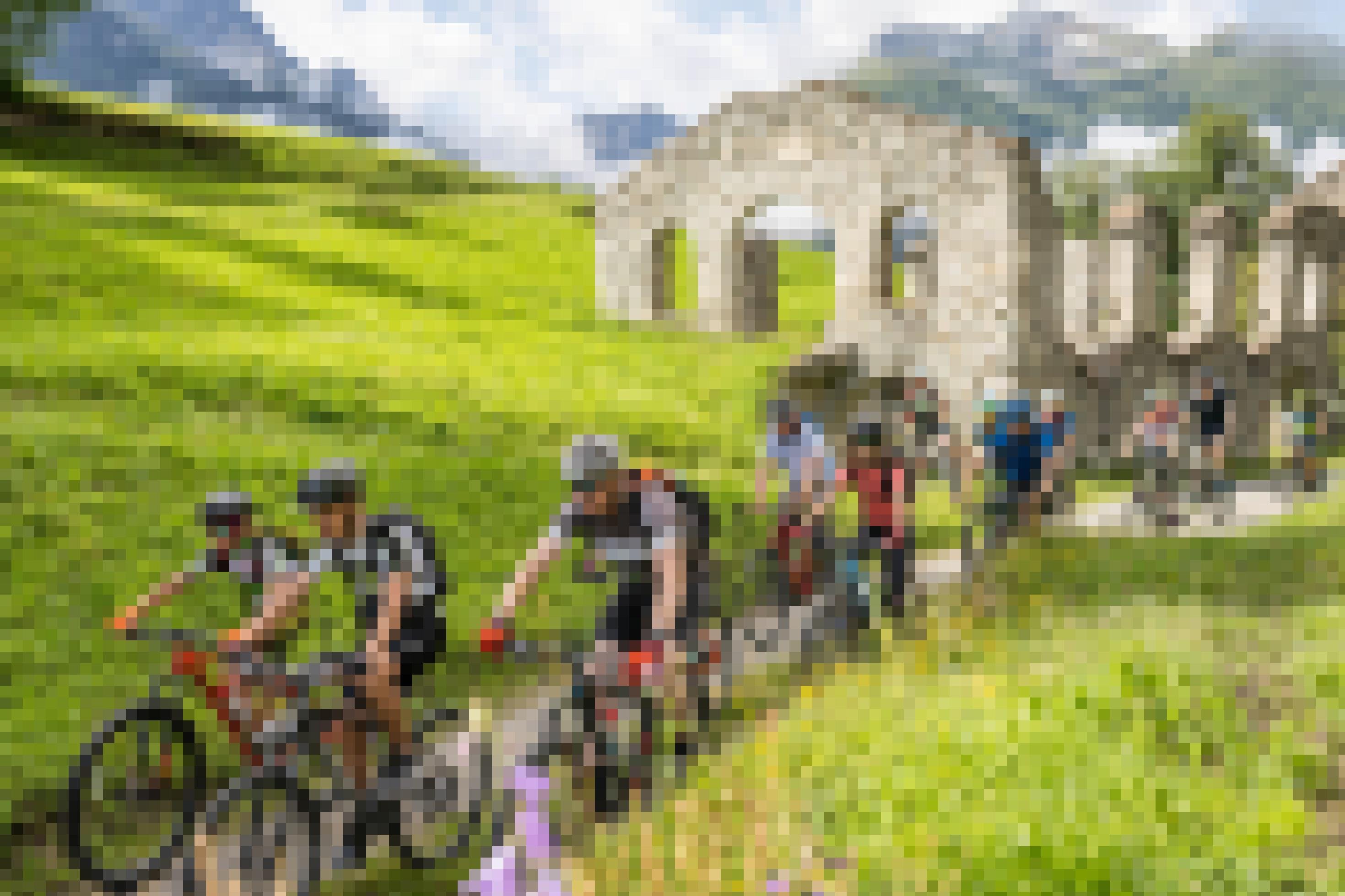 Kinder und Jugendliche fahren Rad an Ruine eines Steinhauses vorbei