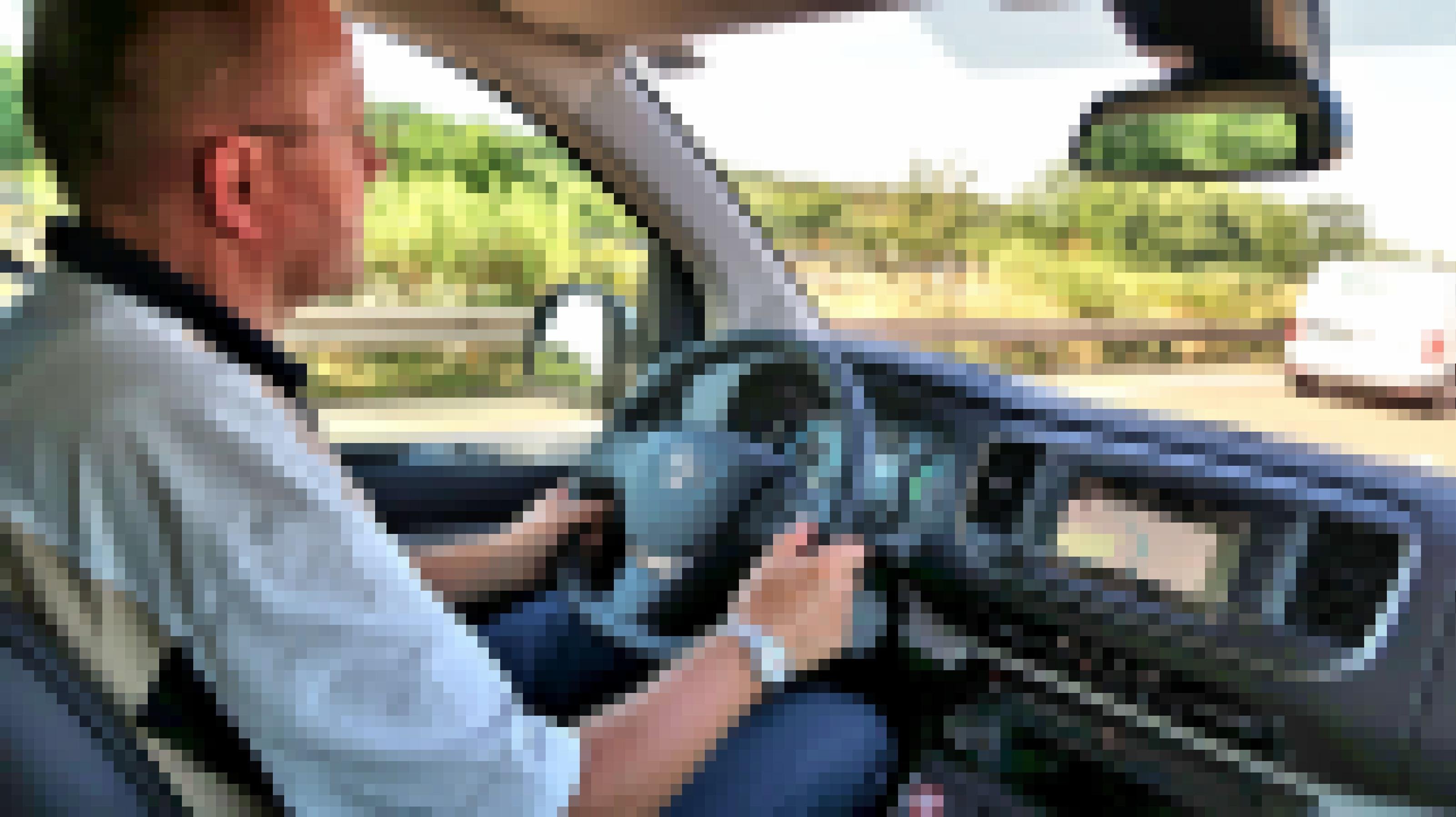 Ein Mann sitzt am Steuer eines Fahrzeugs, das über die Autobahn fährt.