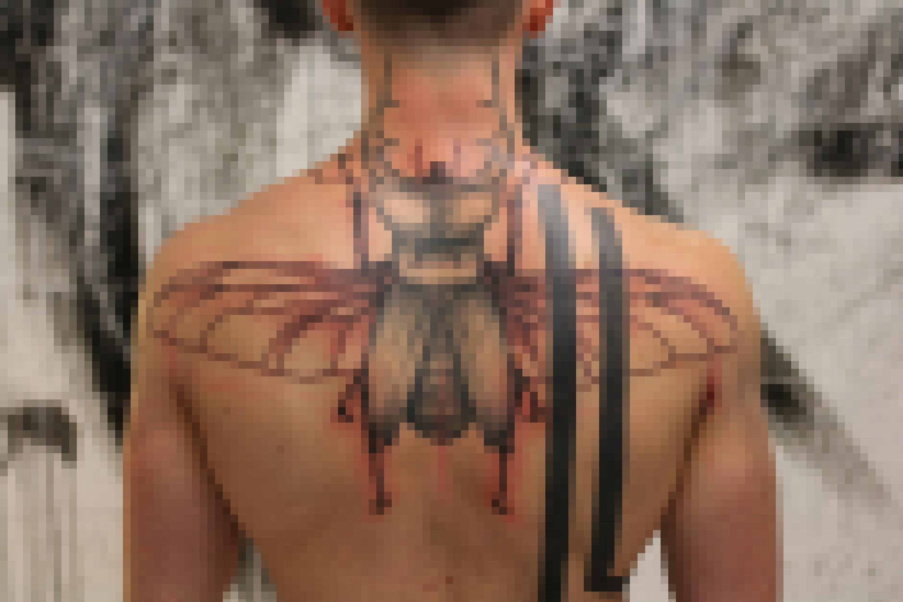 Rücken eine jungen Mannes, der sich das Motiv eines Käfers mit geöffneten Flügeln auf die Schulterblätter tätowieren ließ.