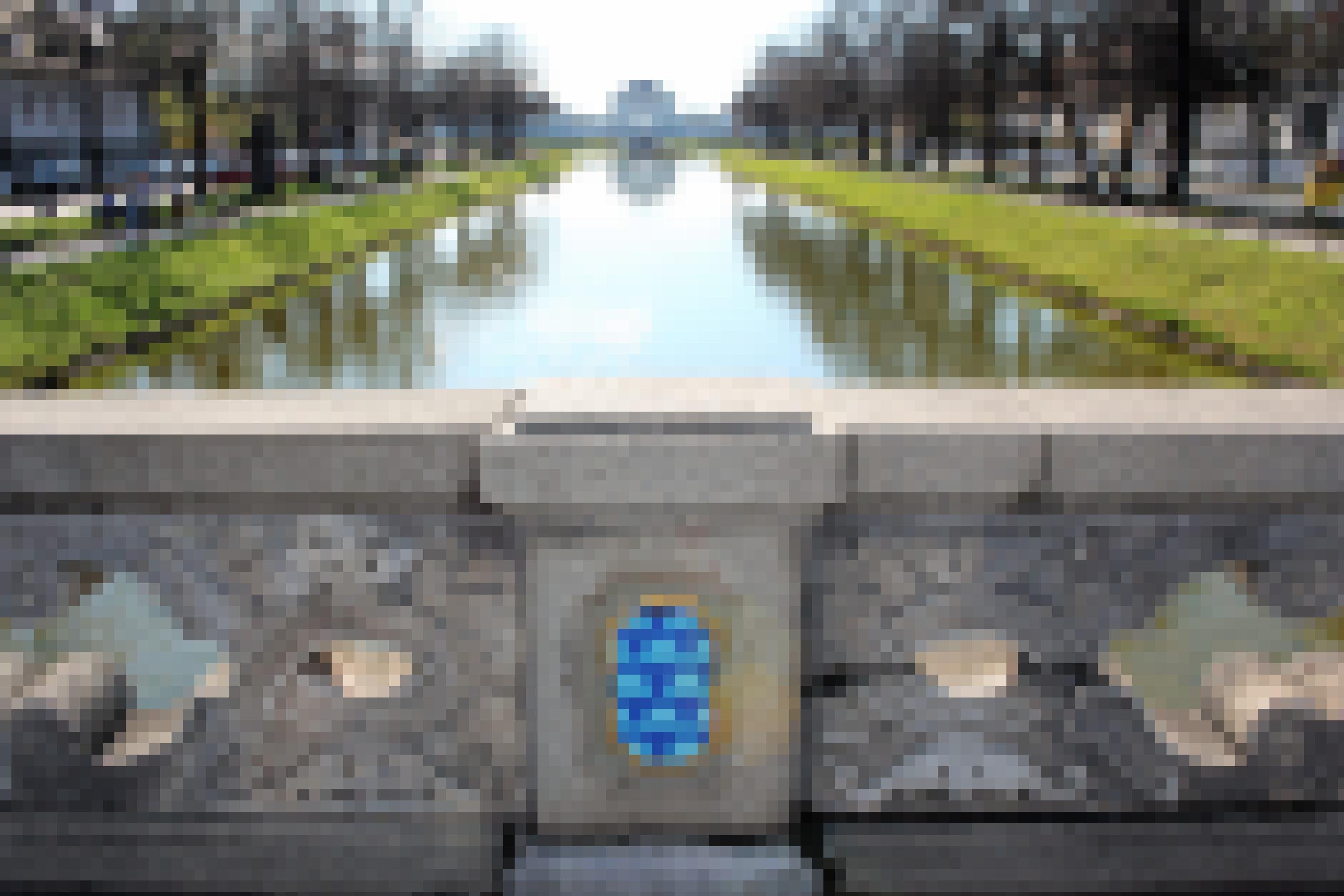 An einer Brücke hat Invader in welligem Blau und in Goldfarbe ein Kunstwerk in Jugendstil angebracht, im Hintergrund das Schloss Nymphenburg.