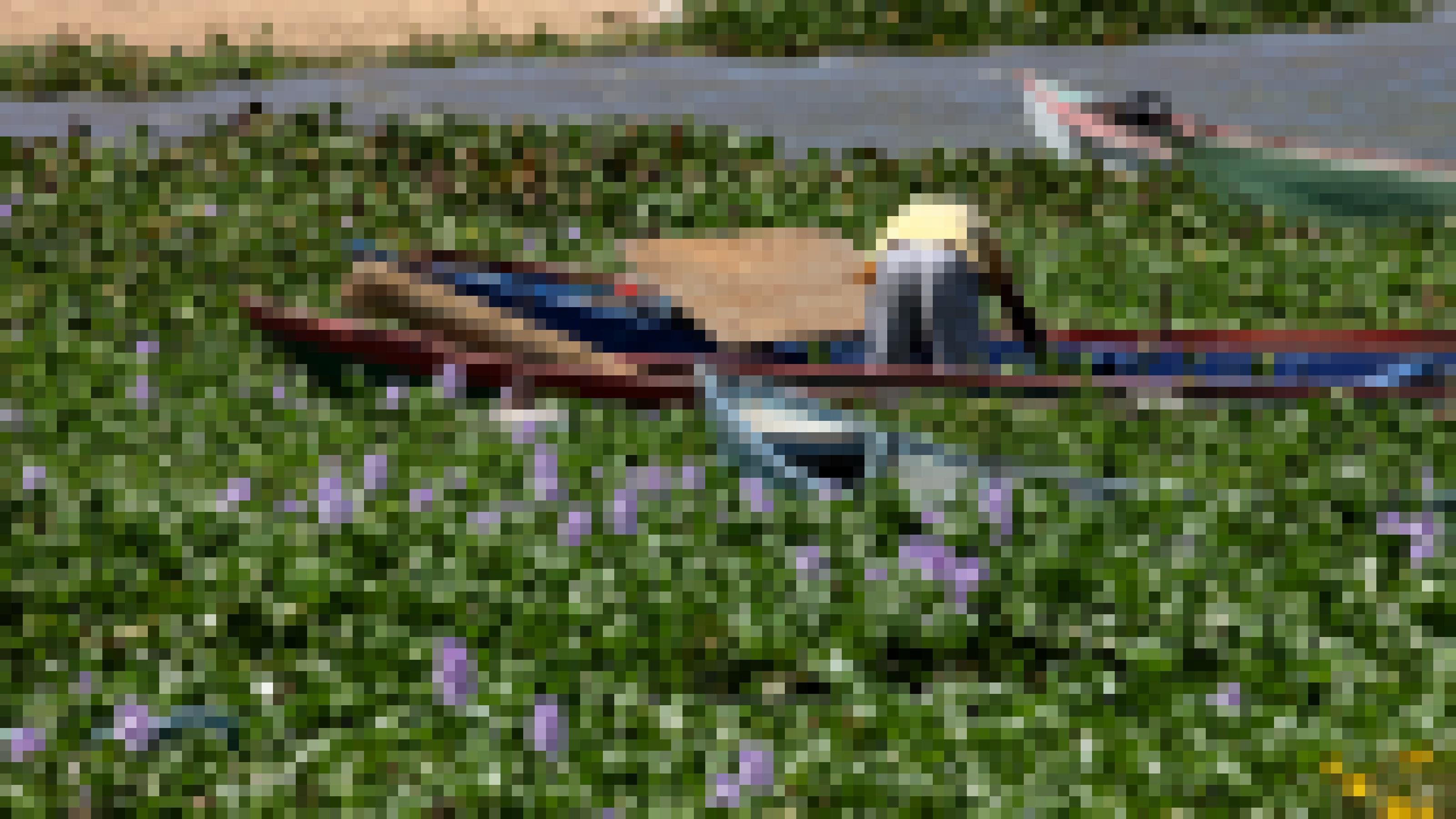 Zahlreiche Boote liegen im Wasser, das vor lauter Pflanzen kaum sichtbar ist. An einem der Boote steht gebückt ein Mensch. Die Pflanzen tragen lilafarbene Blüten.