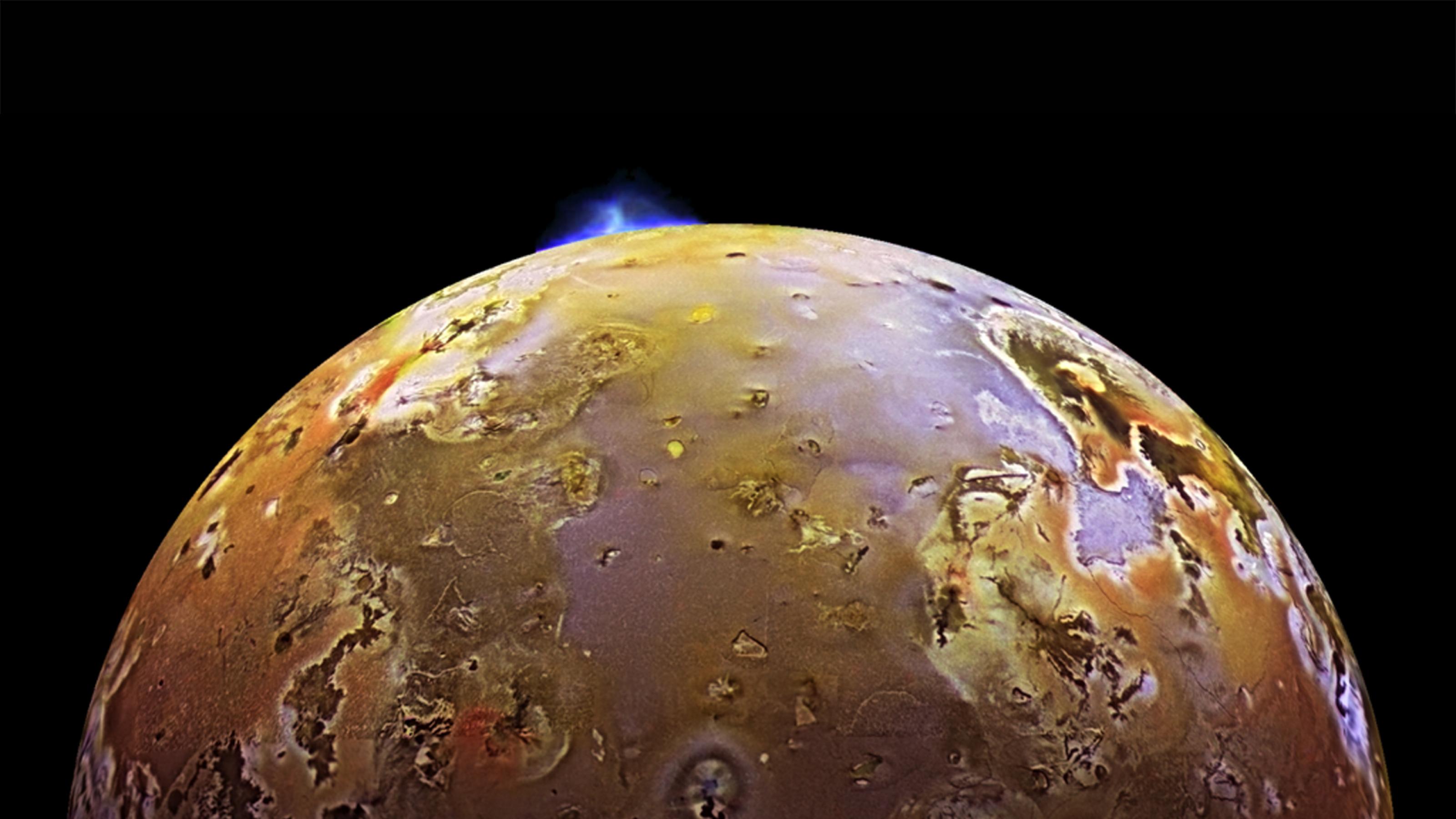 Ein halber Mond Io mit gelber Oberfläche, pockennarbigen grauen und bläulichen Bereichen. Gegen den schwarzen Weltraum zeichnet sich eine helle Eruptionswolke ab, die nach oben aufsteigt.