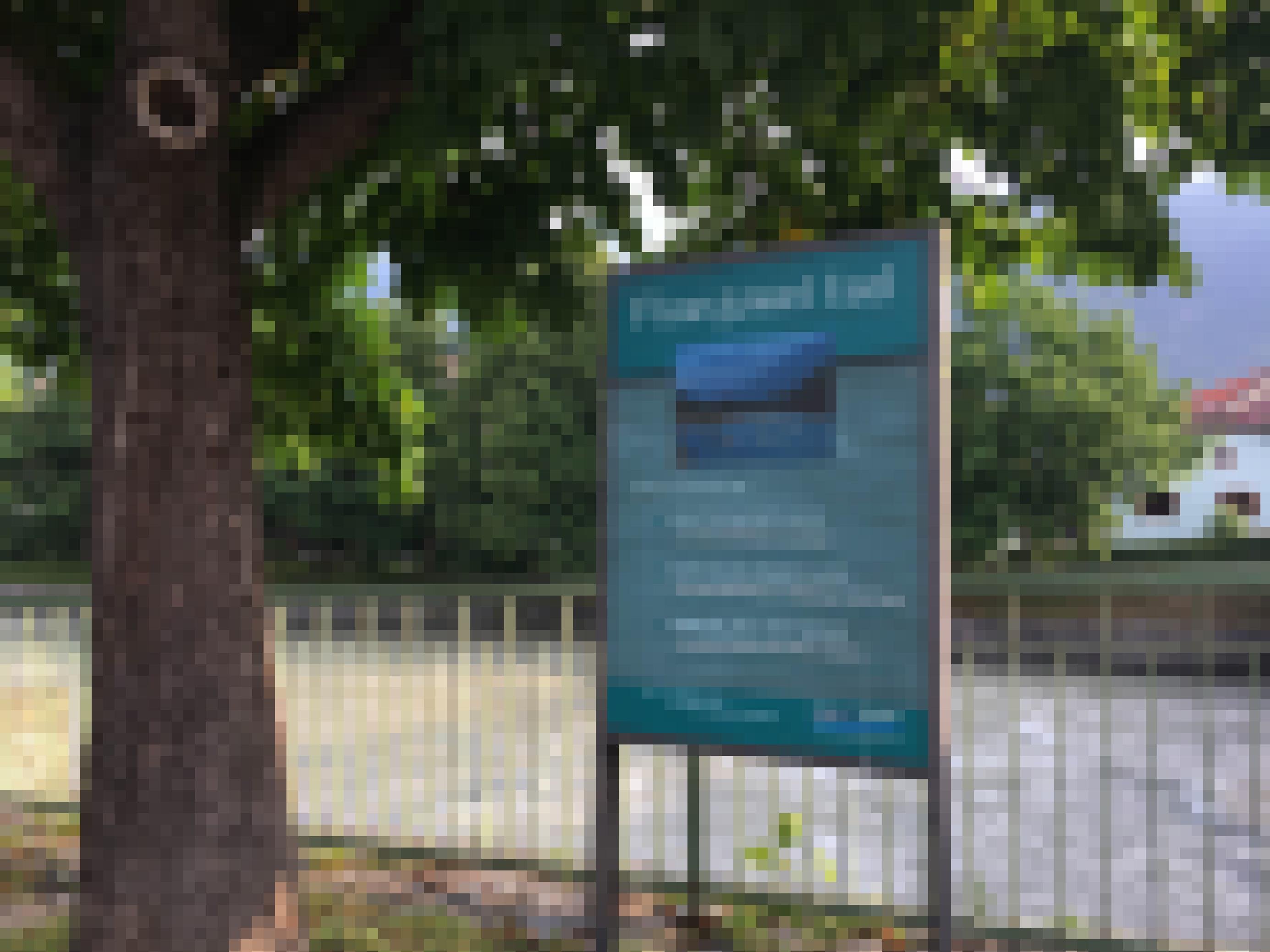 Fluss, Baum, Zaun, Tafel mit Aufschrift „Flussjuwel“ in der Stadt