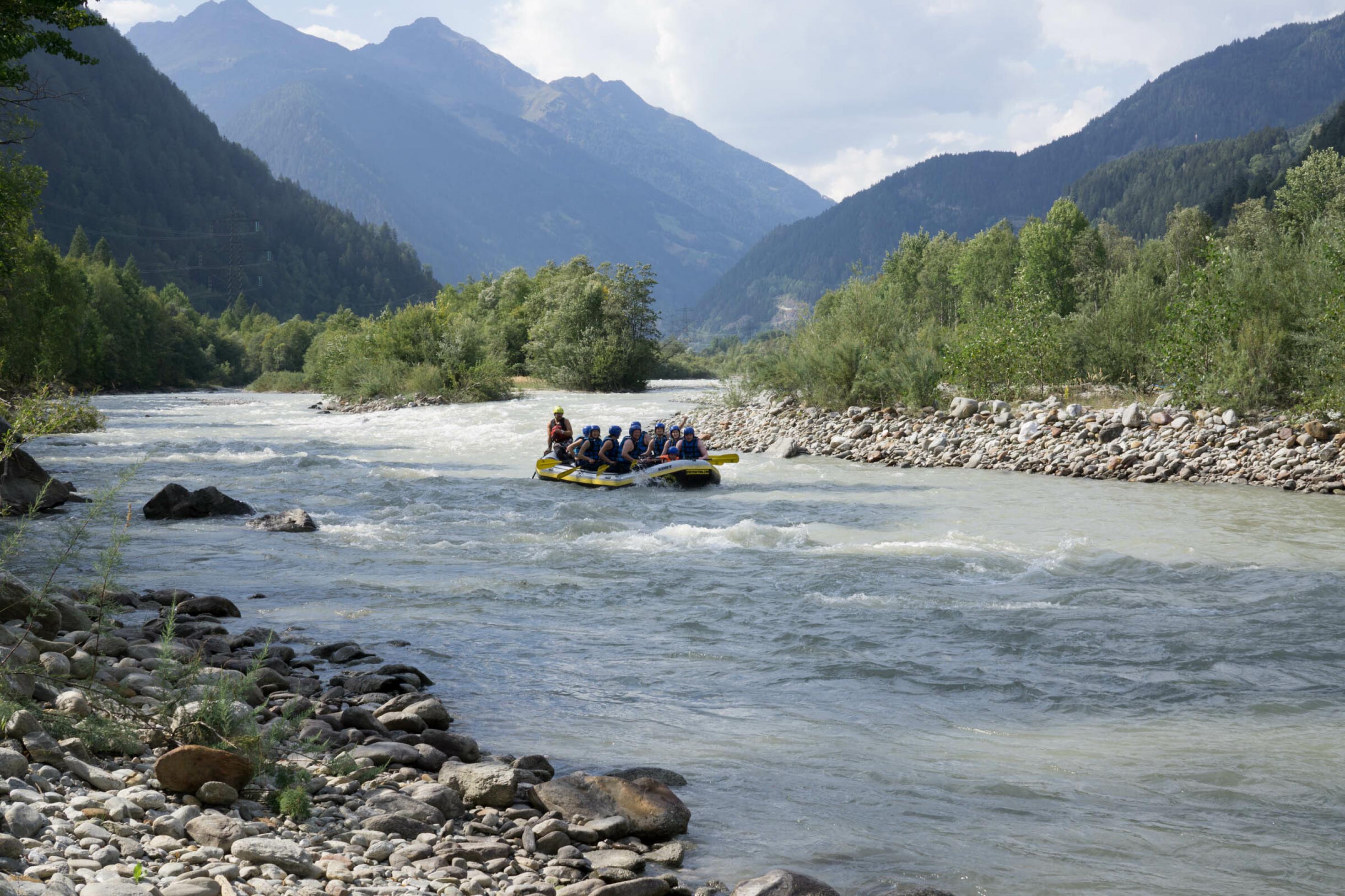 Rafting-Boot auf breitem Gletscherfluss in alpiner Landschaft