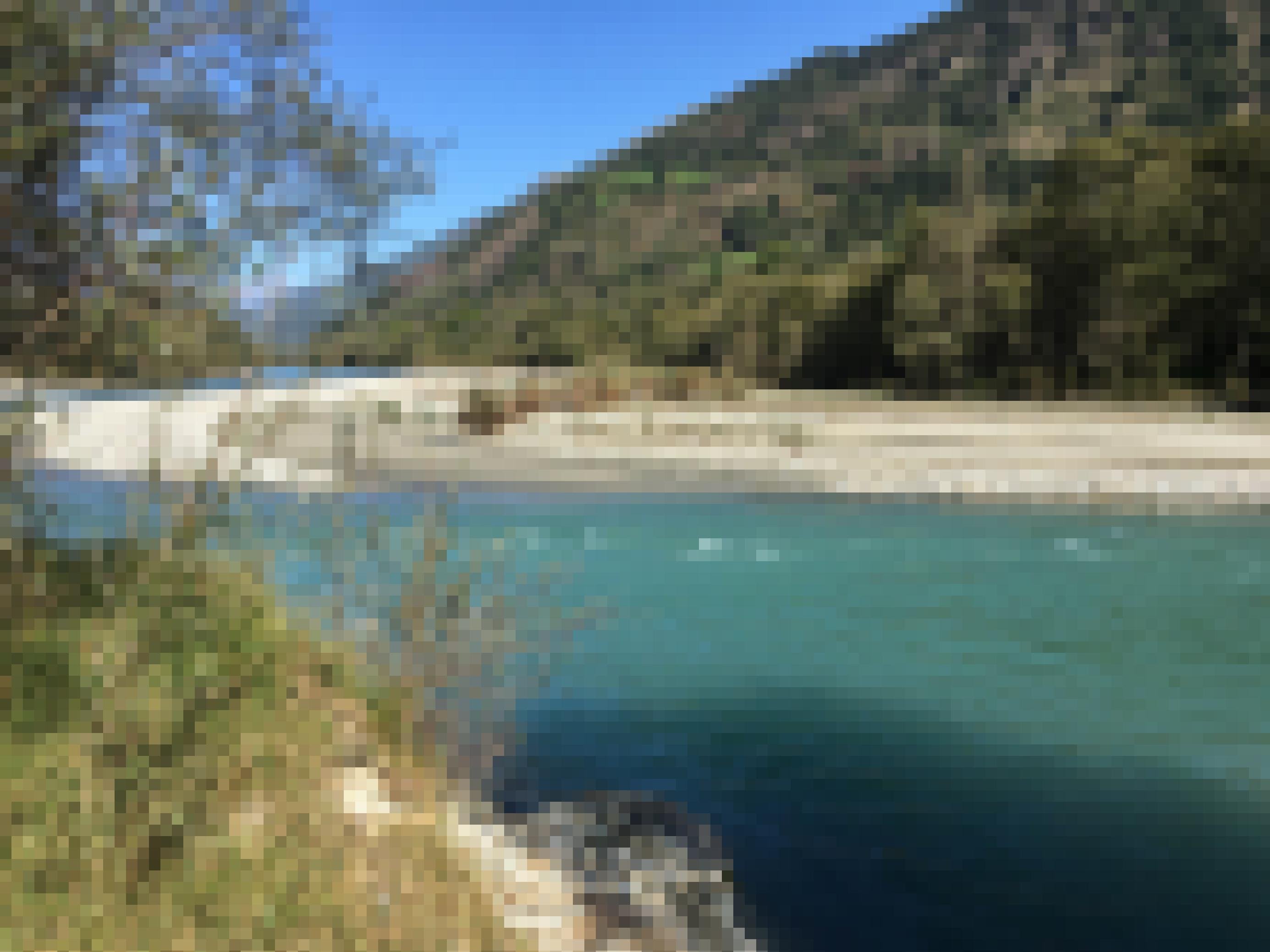 Türkisgrüner Fluss mit Schotterbank, dahinter ein waldbewachsener Berg