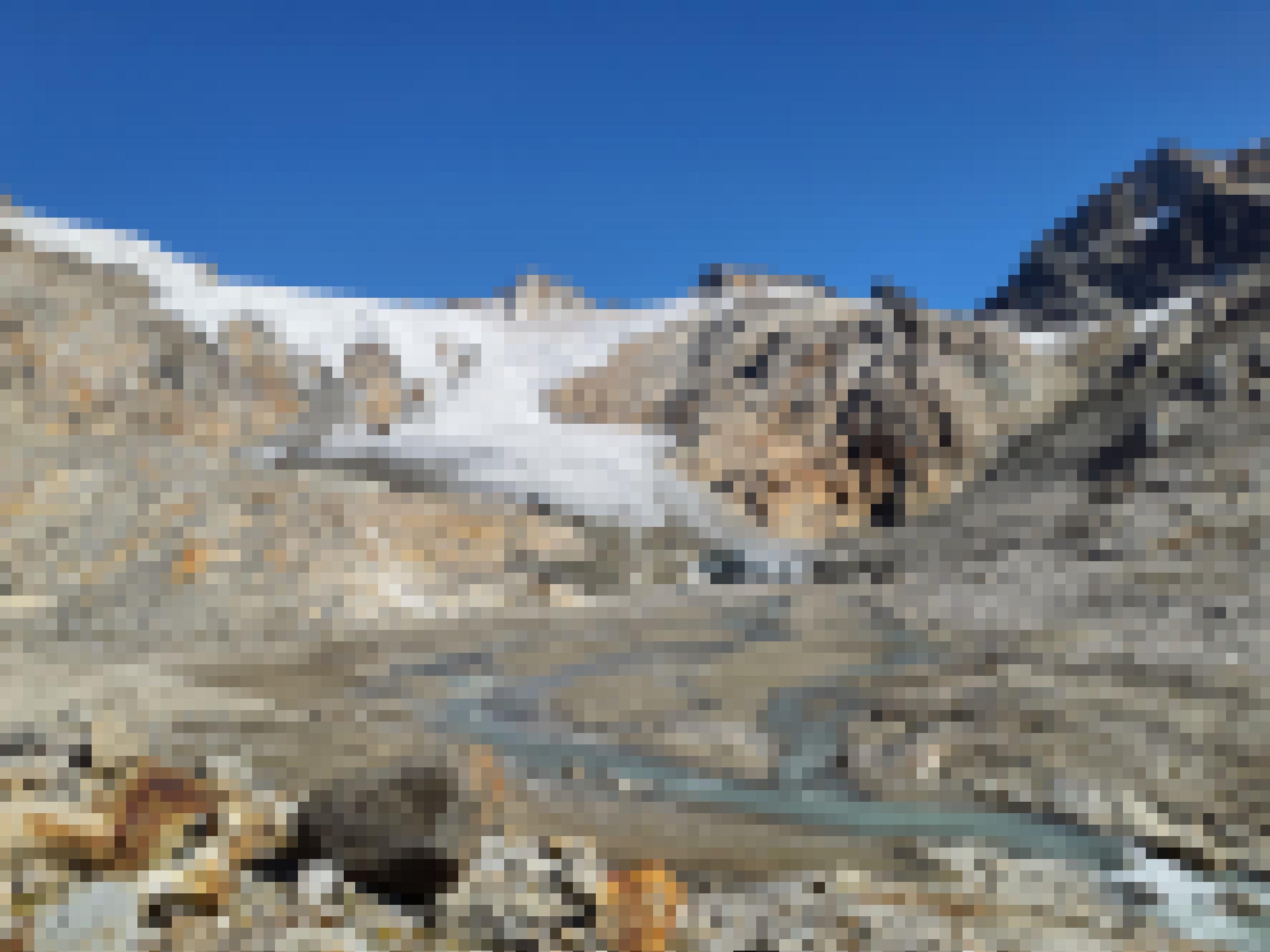 Felsige Berge mit Gletscher, davor das sandige Gletschervorfeld mit türkisgrauem Wasser