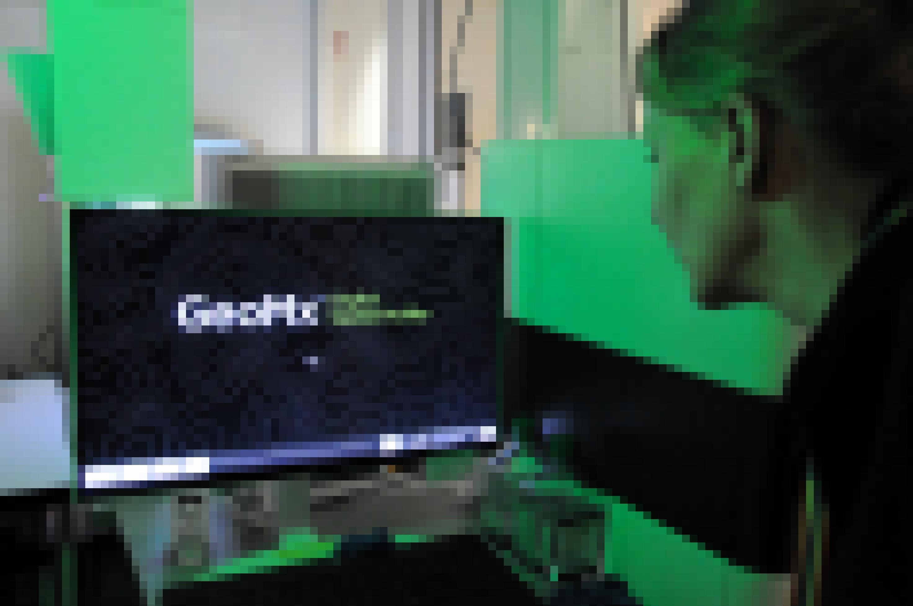 Im Zentrum eines grün beleuchteten Raums steht ein schwarzer Monitor mit der Aufschrift GeoMx. Rechts davon sieht man halb von hinten eine mittelalte Frau, die auf den Monitor blickt.