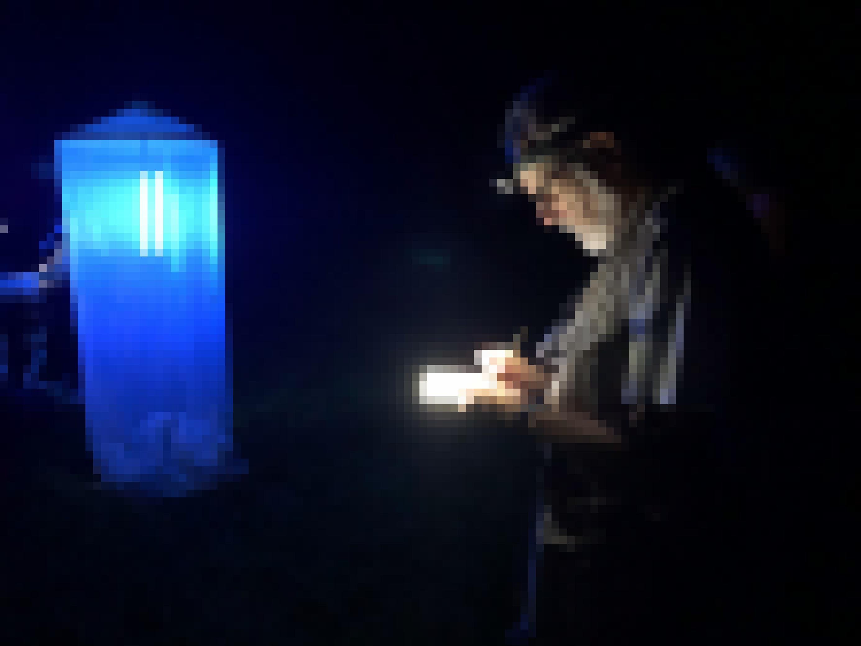 Ein Mann mit weißem Bart, Brille und Stirnlampe schreibt etwas in ein Notizbuch. Im Hintergrund lechtet weiß-blau ein mannshoher Turm aus Gaze, eine Lichtfalle für Nachtfalter.