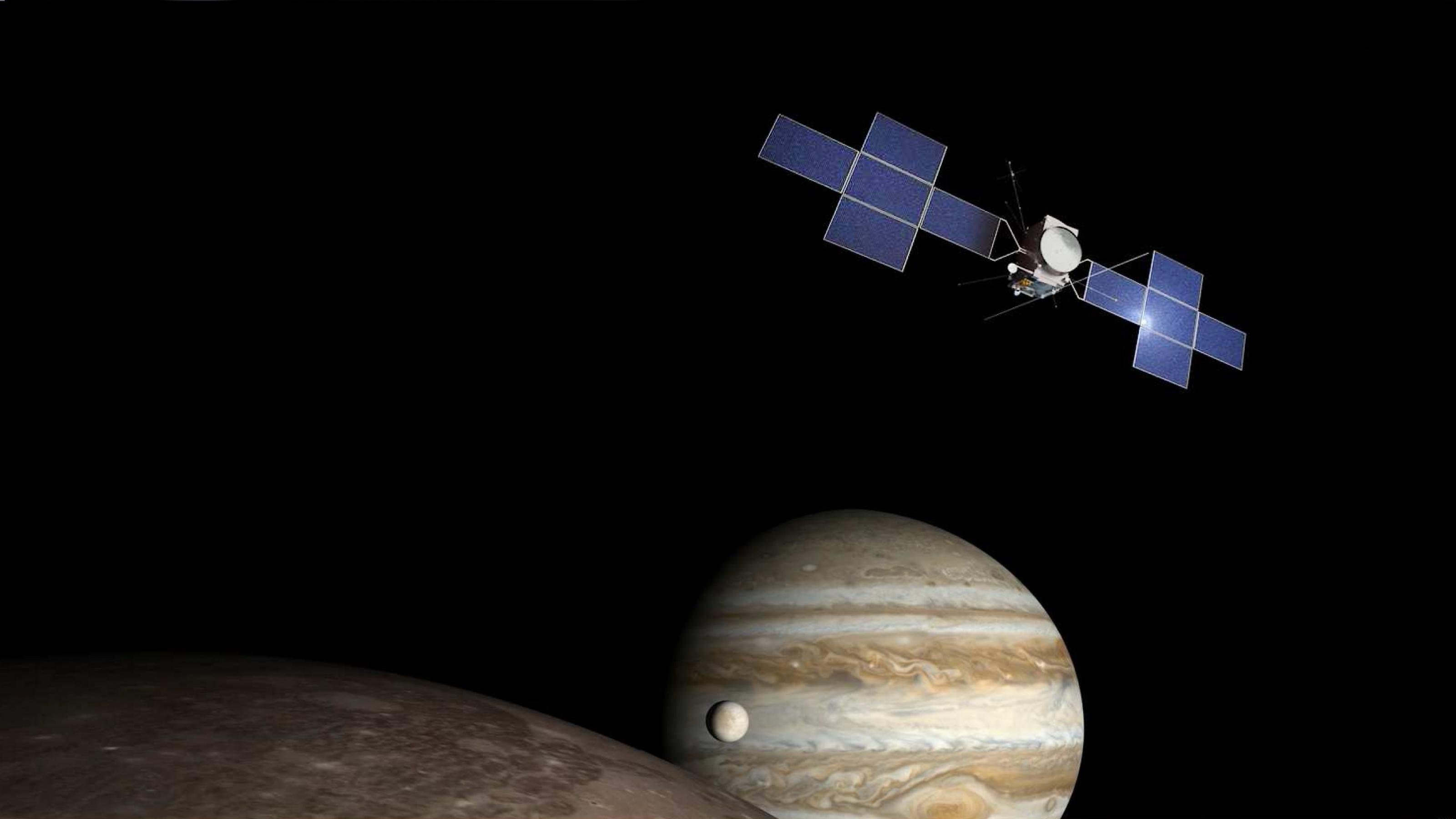 Vor dunklem Hintergrund ist die Raumsonde JUICE zu sehen; am unteren Bildrand rangt der Planet Jupiter mit zweien galileischen seiner Monde ins Bild.